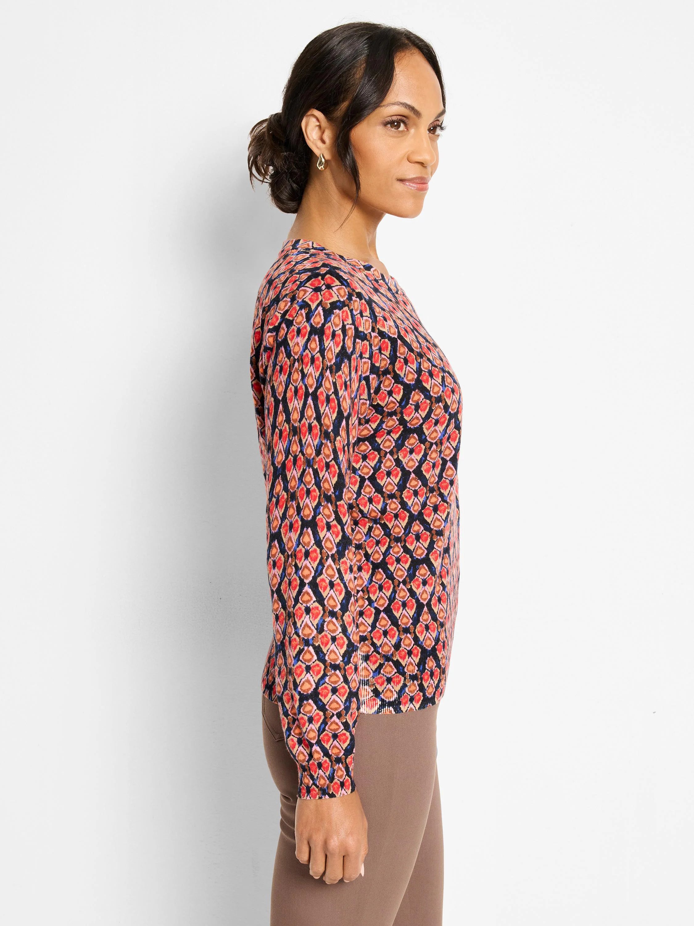 Long-sleeve sweater with an ikat pattern in red, orange, pink, blue, and brown on a dark background.