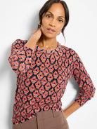 Dark sweater with blurred ikat pattern in reds, oranges, pinks, and blue. Crew neck, long sleeves.
