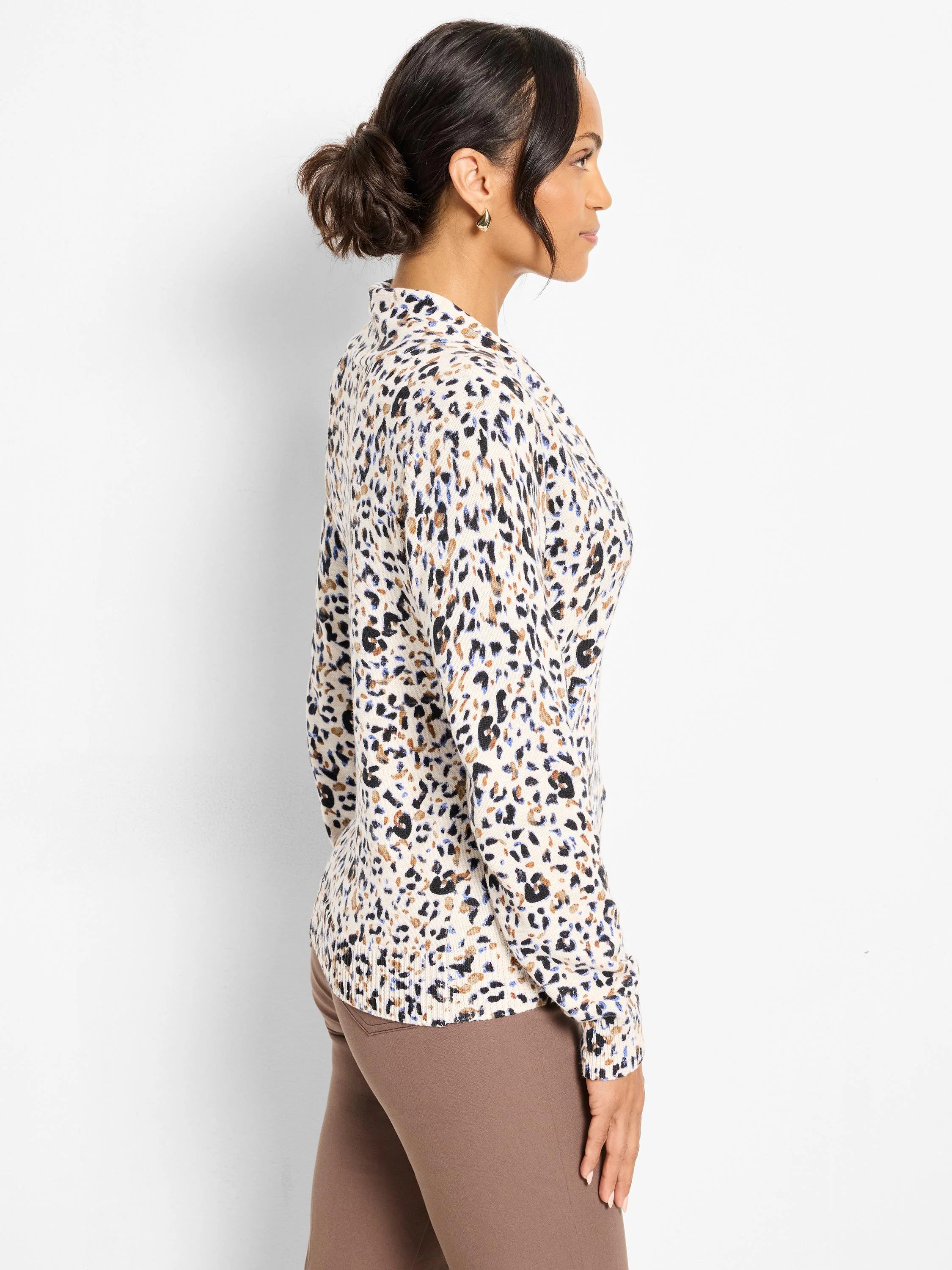 Long-sleeve, off-white sweater with black, brown, and blue leopard-like spots. Features a collared neckline.