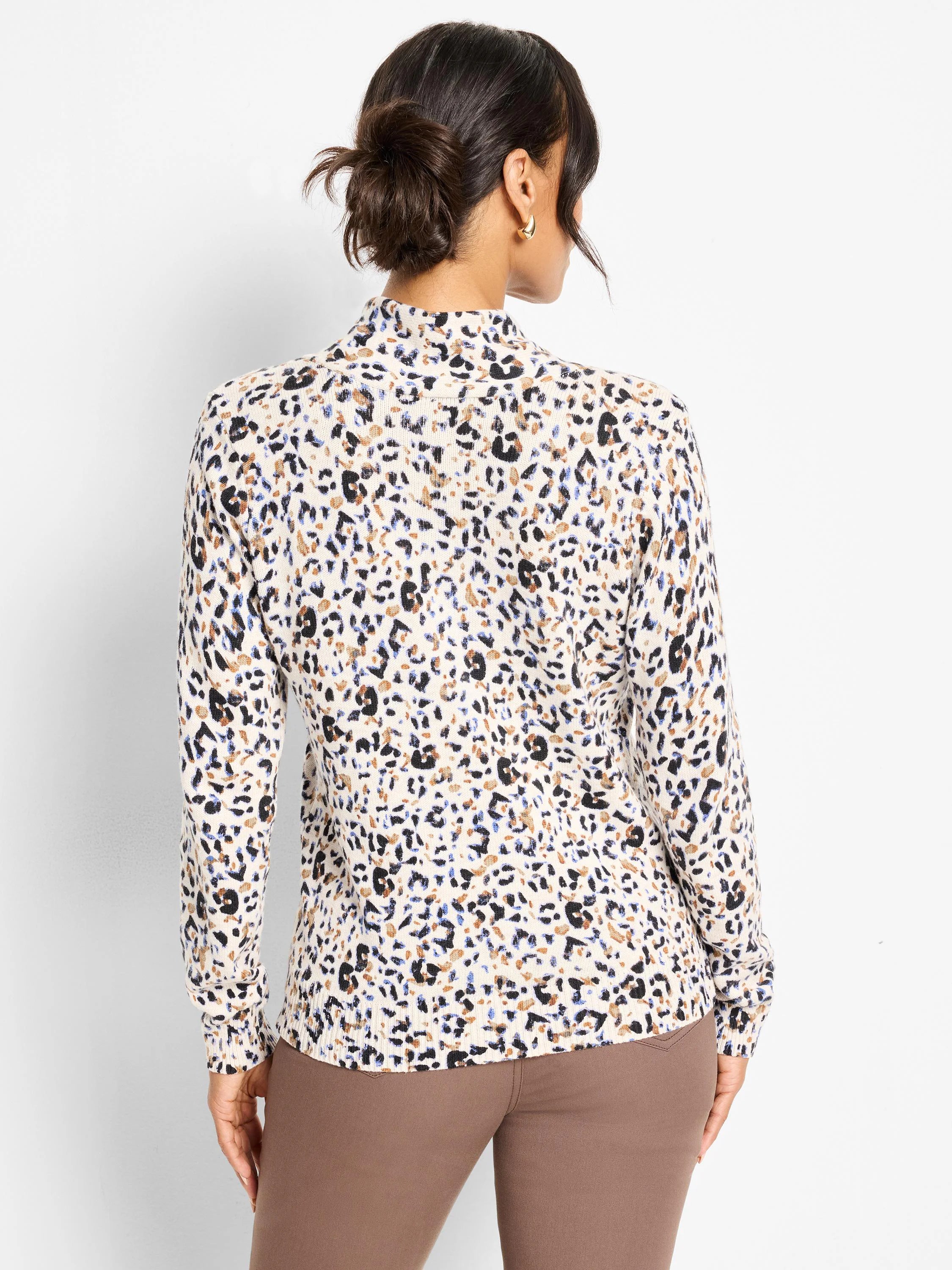 Back view of a cream mock-neck sweater with black, brown, and blue cheetah print spots.