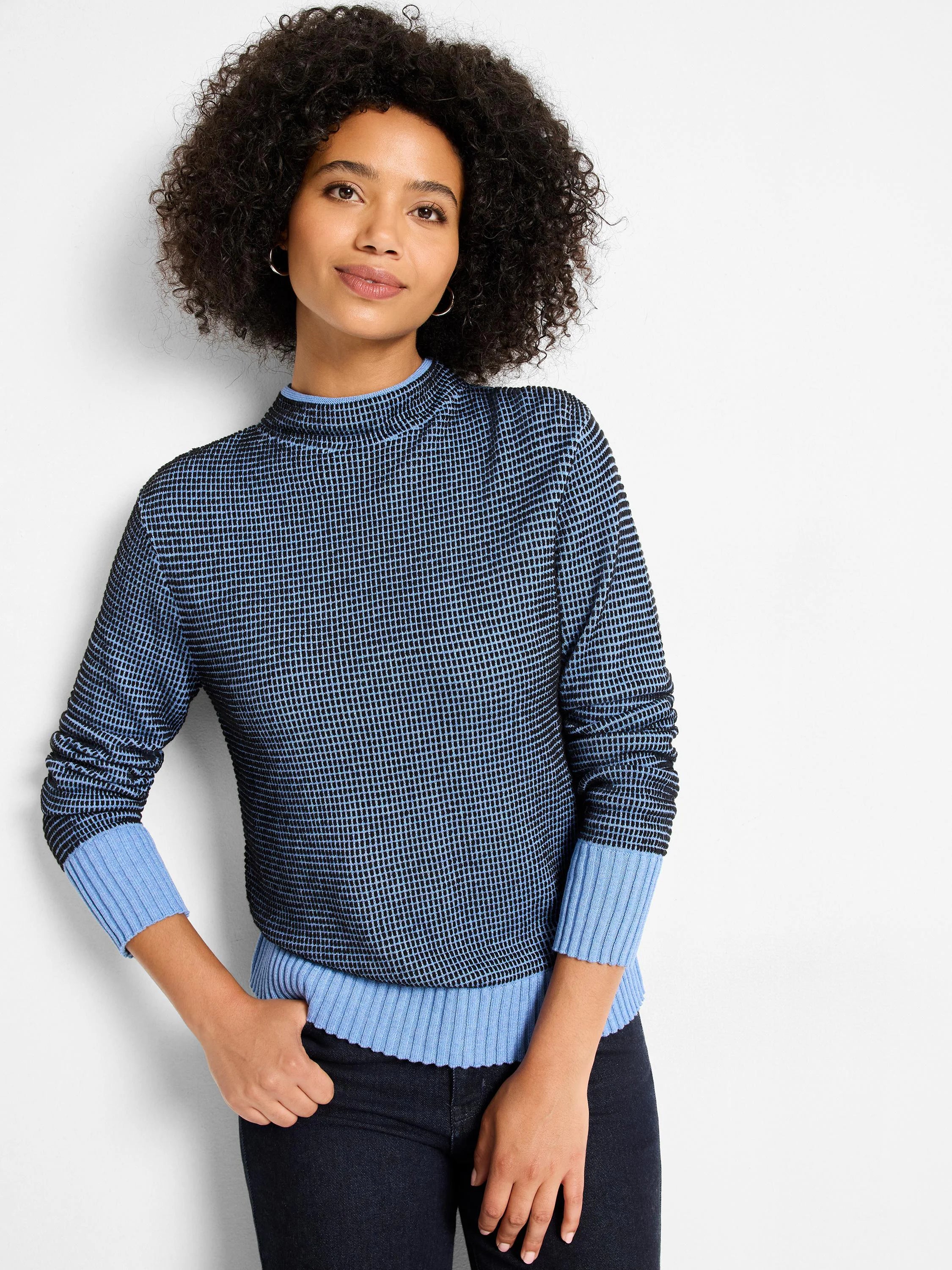 Funnel neck sweater in dark blue and light blue pixel knit. Features ribbed light blue cuffs and hem.