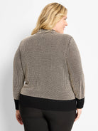 Black and cream pixel knit funnel neck sweater, shown from behind. Features ribbed black cuffs and hem.