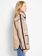 Tan quilted barn coat with black trim. Its surface shows a check pattern formed by diagonal stitches.