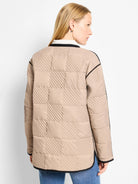 Tan barn coat with black trim. Quilted in a checkered pattern with diagonal stitching.