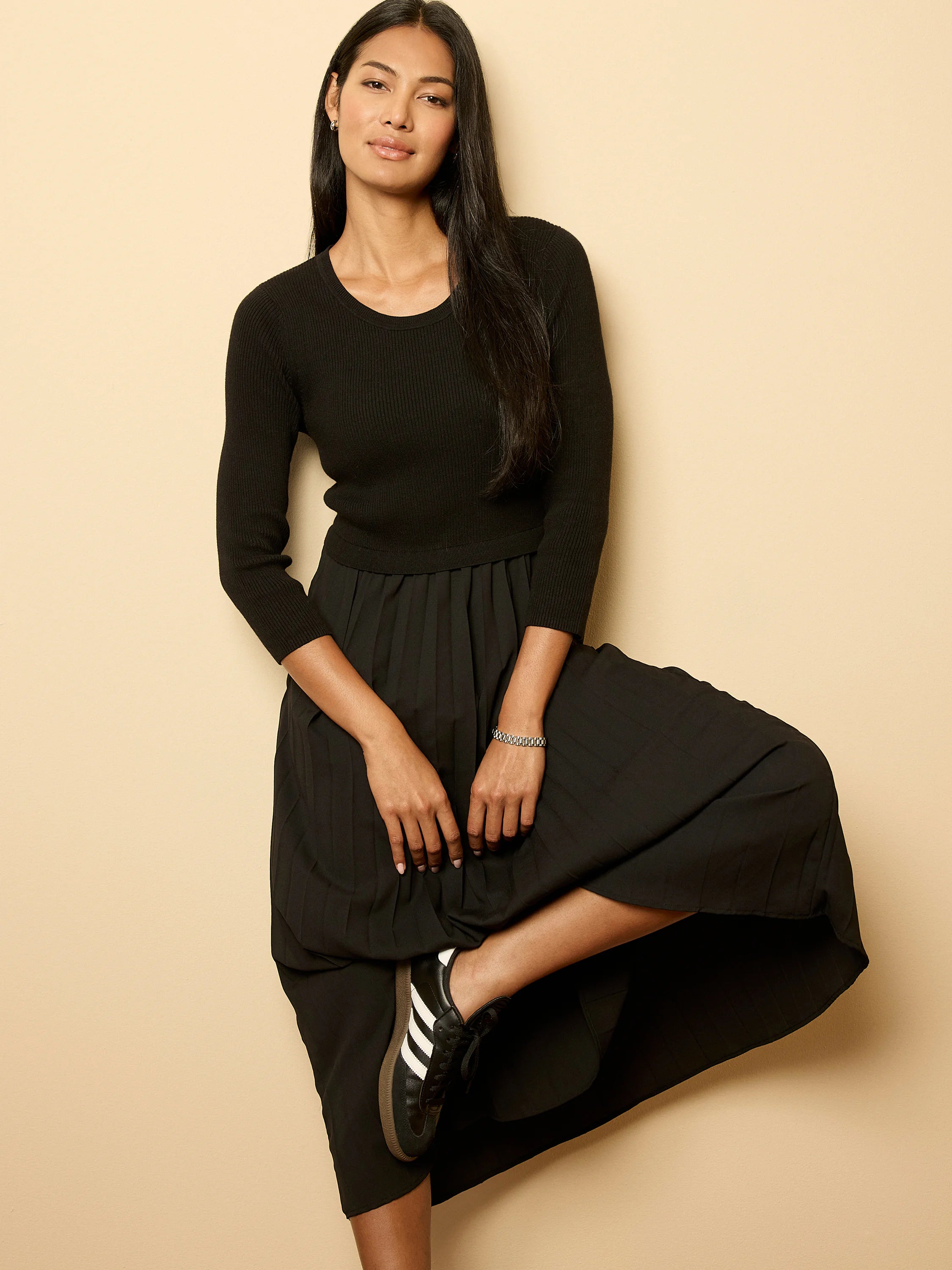 Black ribbed knit top dress with a pleated midi skirt.
