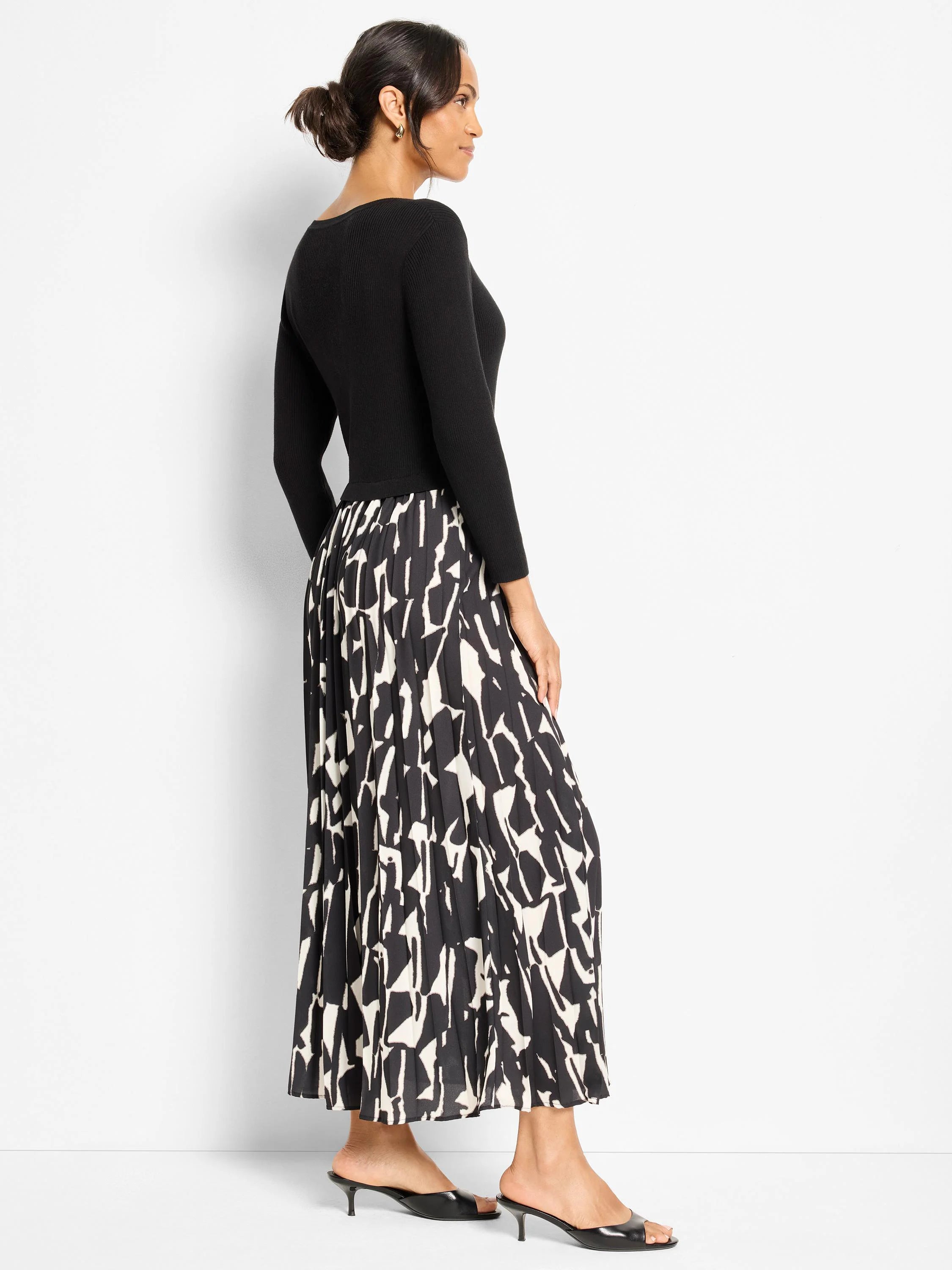 Long-sleeved black dress with a pleated maxi skirt featuring an abstract black and off-white pattern.