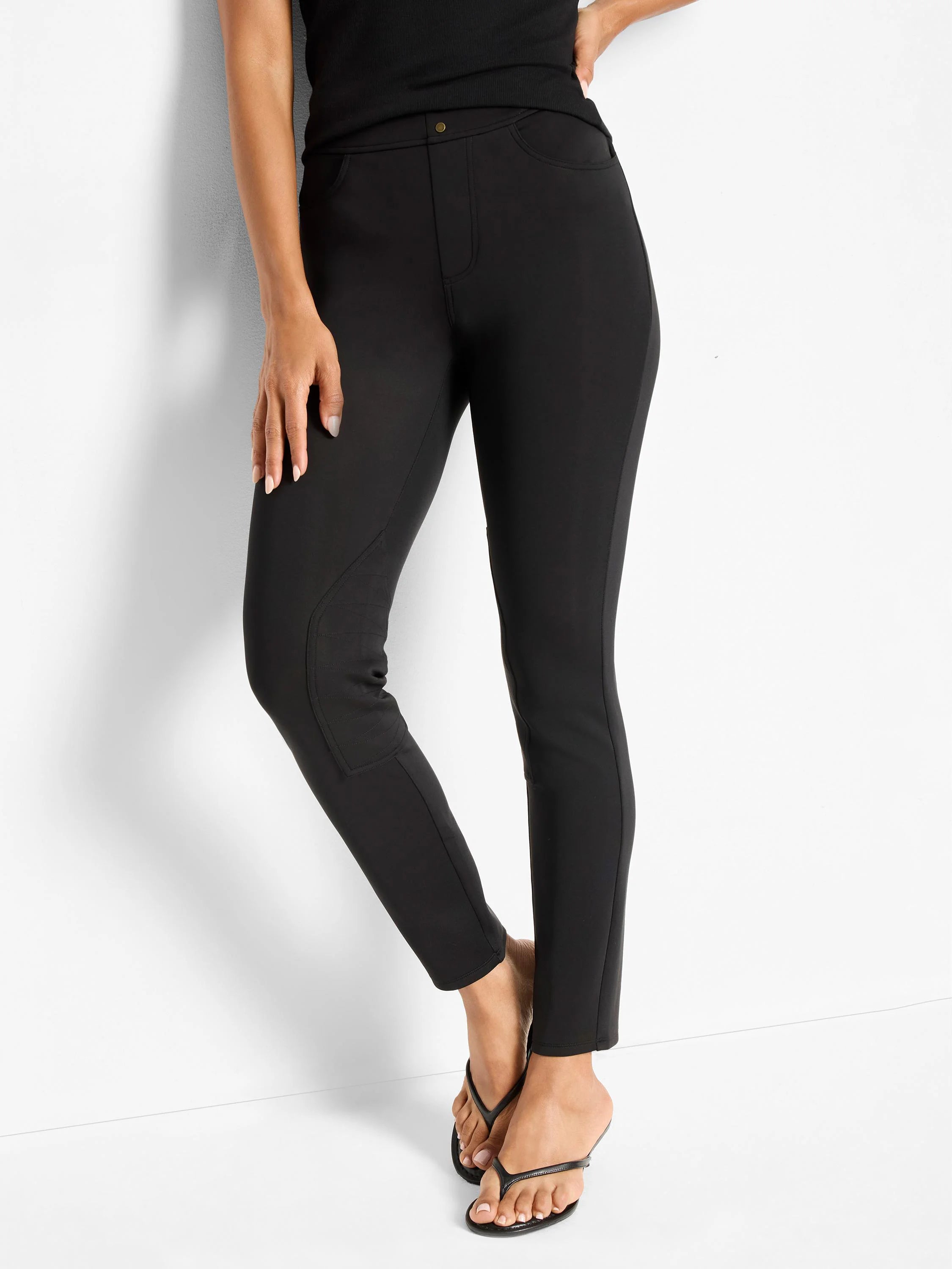 Black, slim-fit riding pants with faux front pockets, seamed knee panels, and an ankle length.