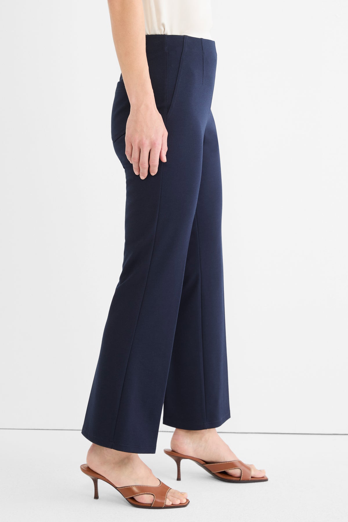 Navy high-waist trousers featuring a slim fit through the thigh, slight flare, and a cropped length.
