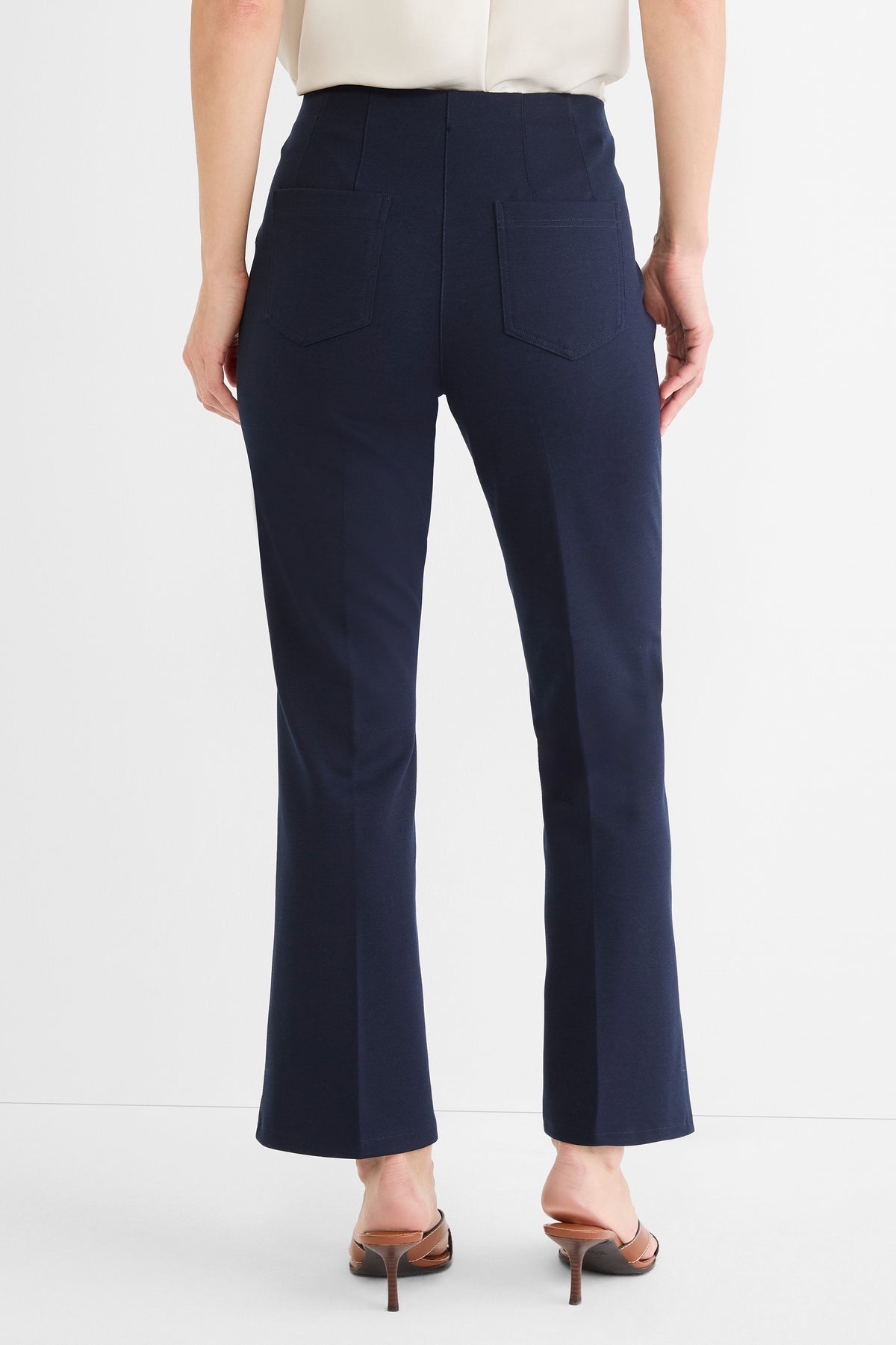 Navy high-waist cropped pants with a slight flare and two prominent rear patch pockets are shown.