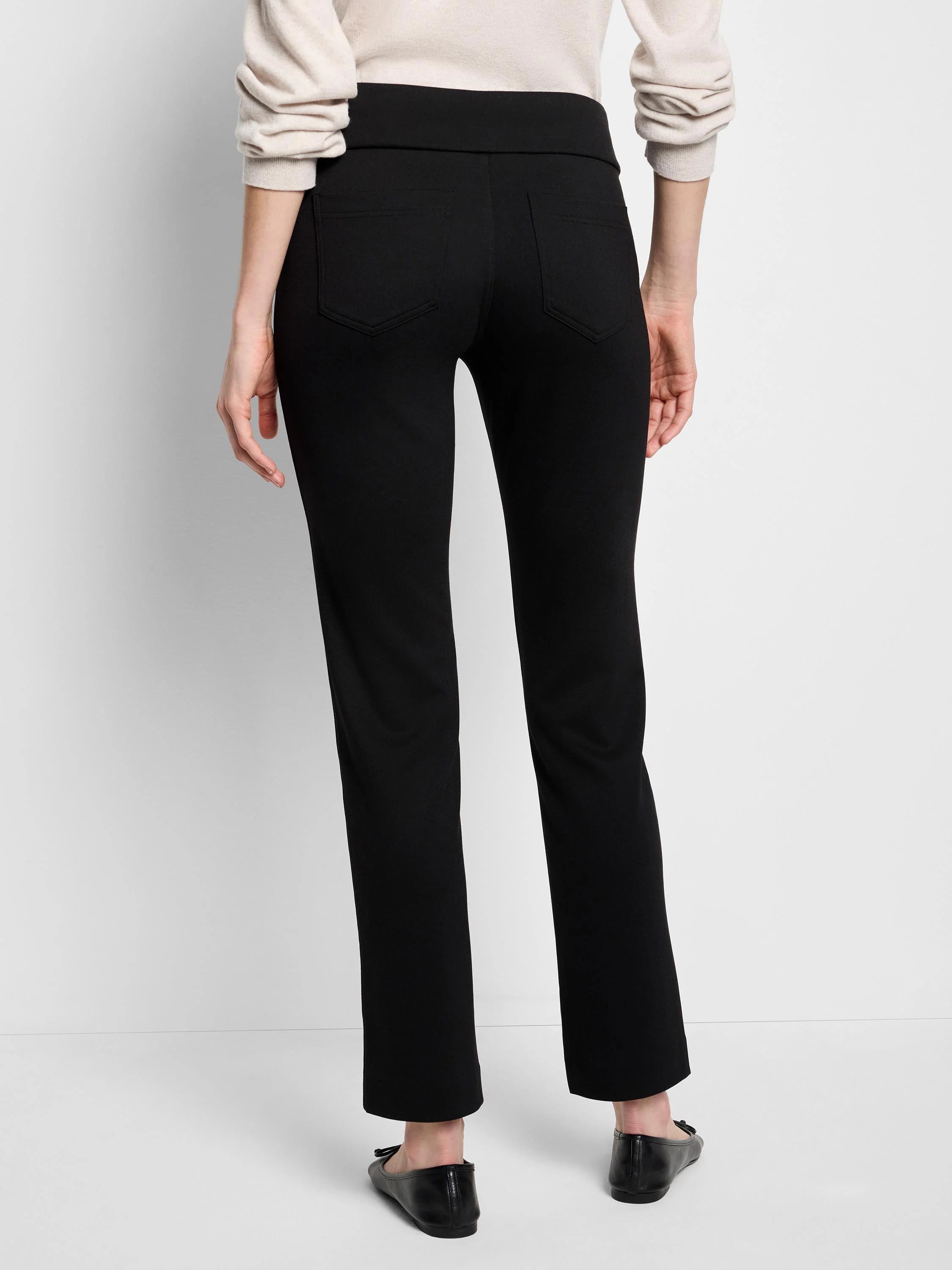 Black straight-leg pants with a pull-on waistband and back pockets.  Model is wearing flats.