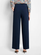 Navy wide-leg pants on a model. Features sleek fabric, a high waist, and prominent front creases down each leg.