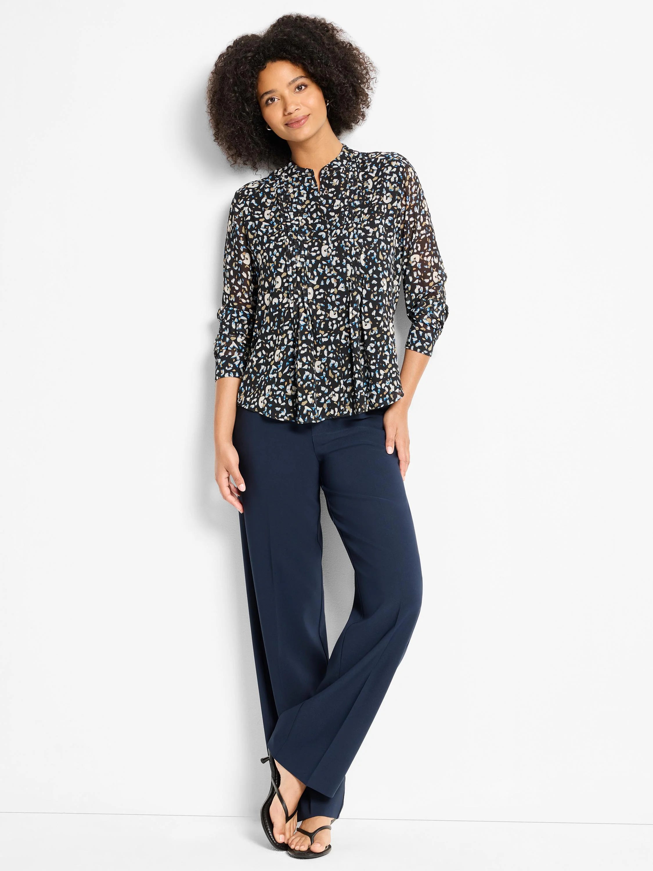 Black top with abstract blue, cream, tan cheetah print. Features mandarin collar, pintucks, 3/4 sleeves, tucked in.