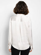Light beige satin shirt, long sleeves with buttoned cuffs, curved hemline.  Back view.