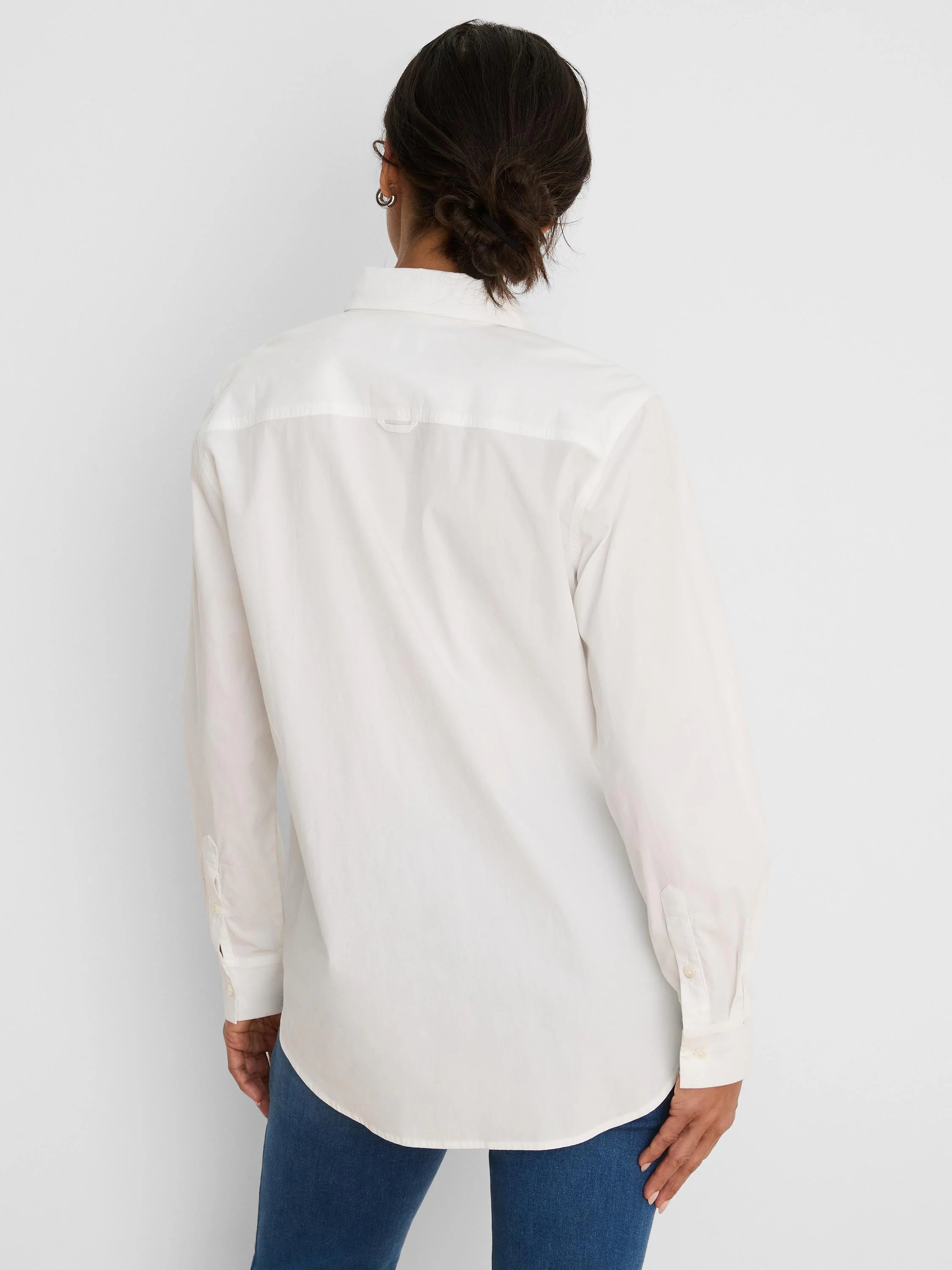 Back view of a white long-sleeved shirt with buttoned cuffs, a back yoke, and a locker loop.