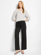 White collared button-down shirt with vertical black painted stripes and two chest pockets.