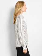 White shirt with vertical black brushstroke stripes. Features a chest pocket with horizontal stripes and long sleeves.