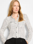 Cream button-up shirt with black irregular vertical painted stripes, a collar, and two chest pockets.