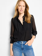 Black chiffon top with a band collar, pleated front placket, 3 white buttons, and sheer long sleeves.