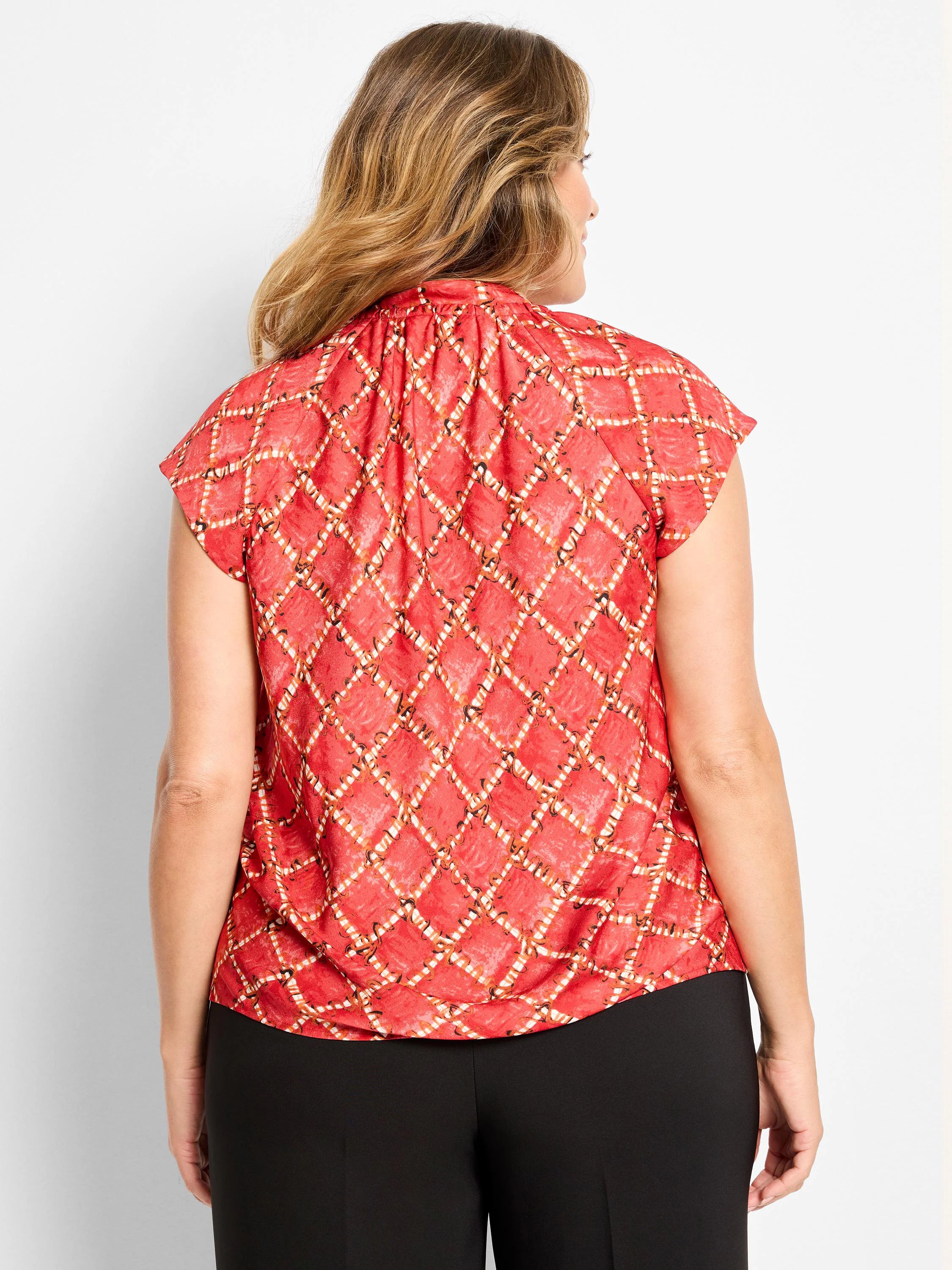 Red cap sleeve top with white, orange, and black squiggle check pattern. Gathered high collar.