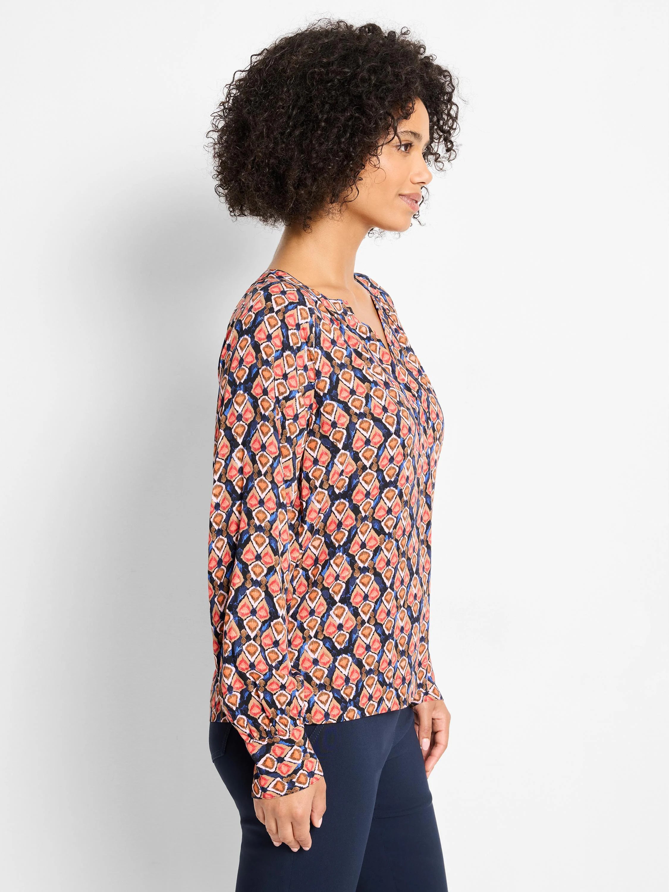 Ikat top: peach, tan, blue diamond pattern on dark fabric. Long sleeves, notch neck.