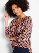 V-neck top with 3/4 sleeves, featuring a geometric ikat print in navy, terracotta, coral, and tan colors.