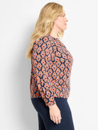 Long-sleeved top, navy blue with coral, orange, light blue ikat pattern of stylized diamond shapes.