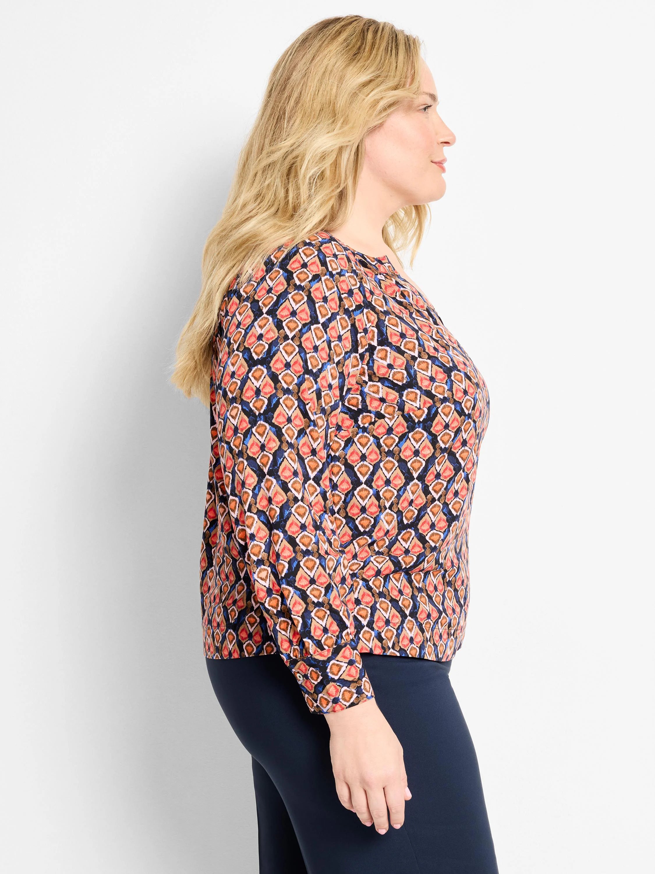 Long-sleeved top, navy blue with coral, orange, light blue ikat pattern of stylized diamond shapes.