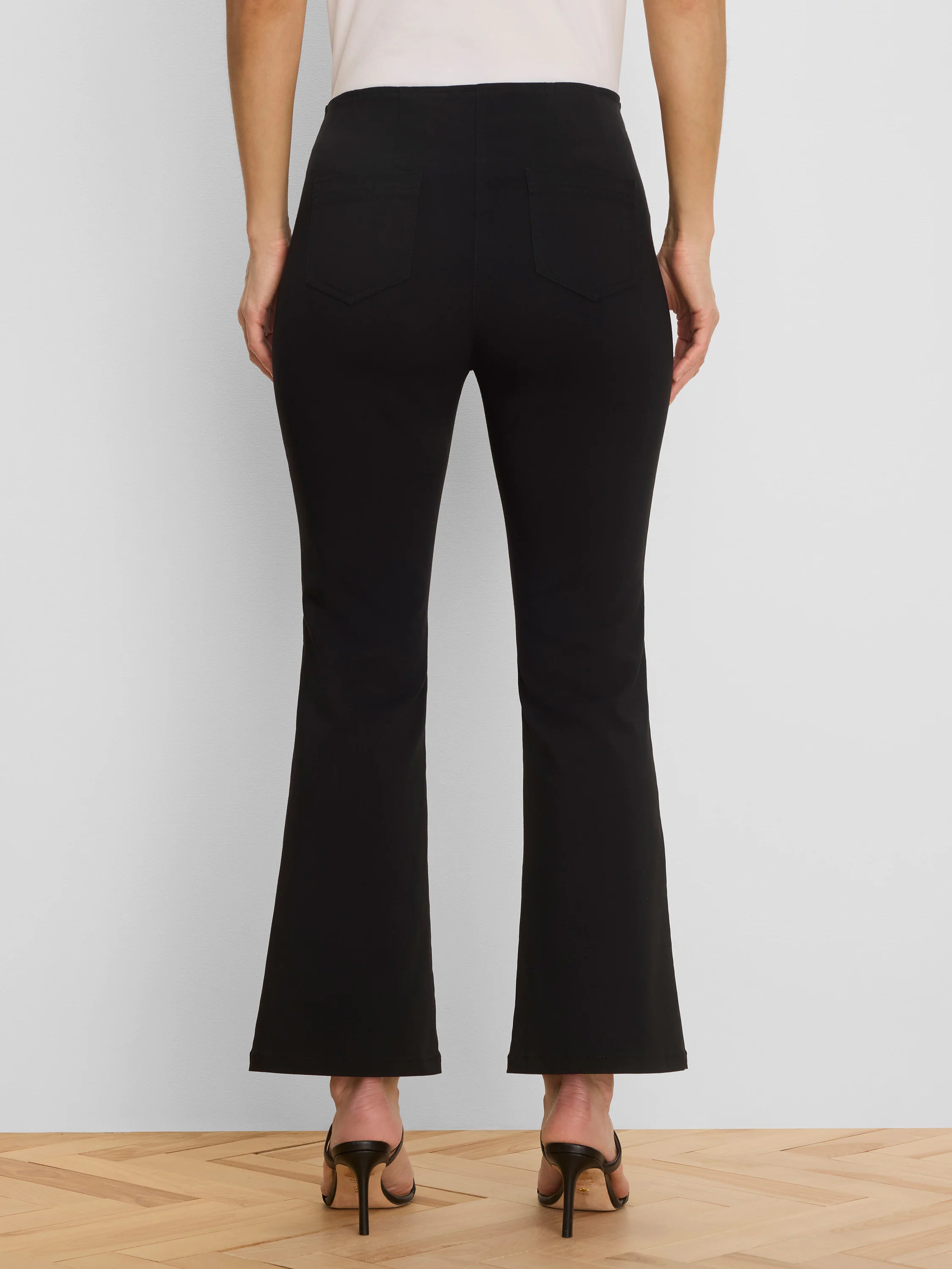 Black bootcut pants with two visible back patch pockets, shown from the rear on a model.