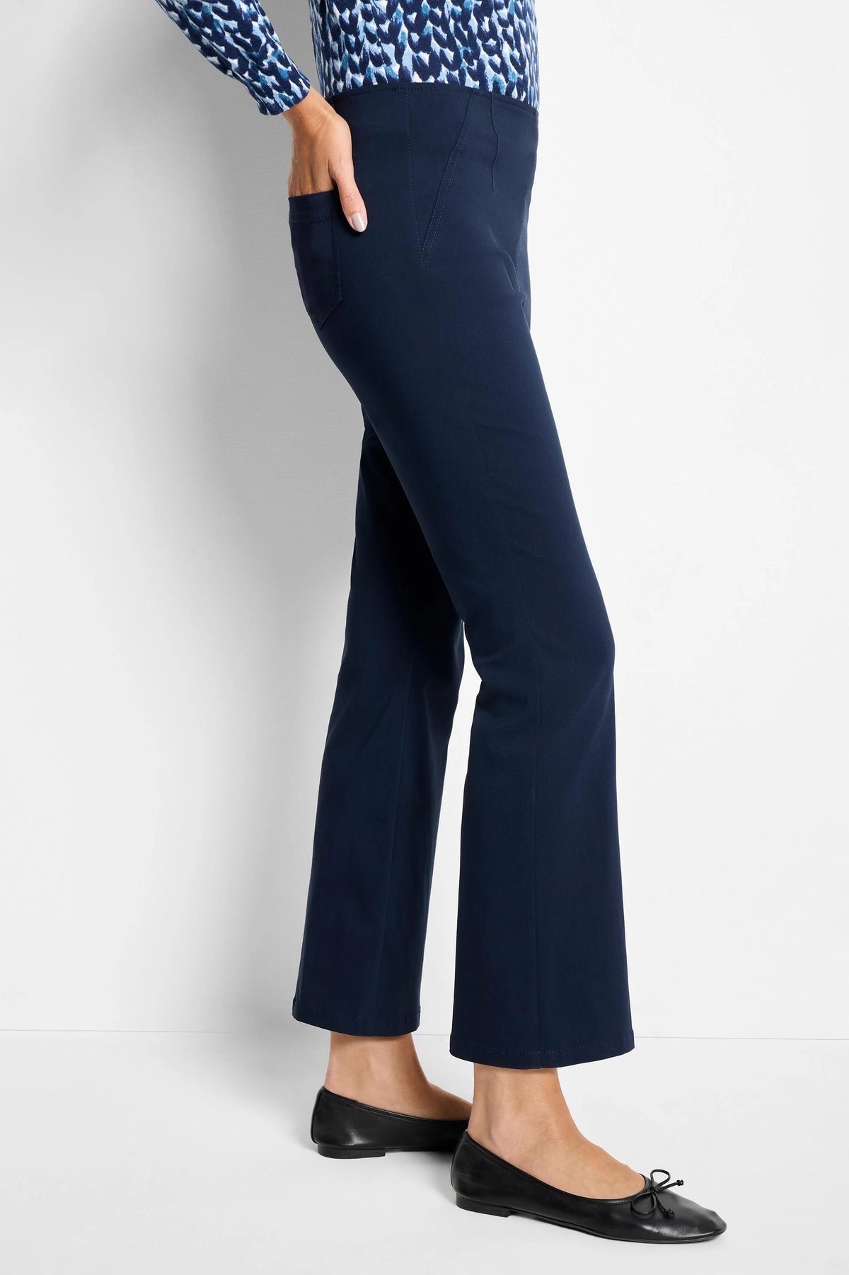 Navy blue bootcut pants with subtle vertical seam details and a side pocket, modeled from the side.