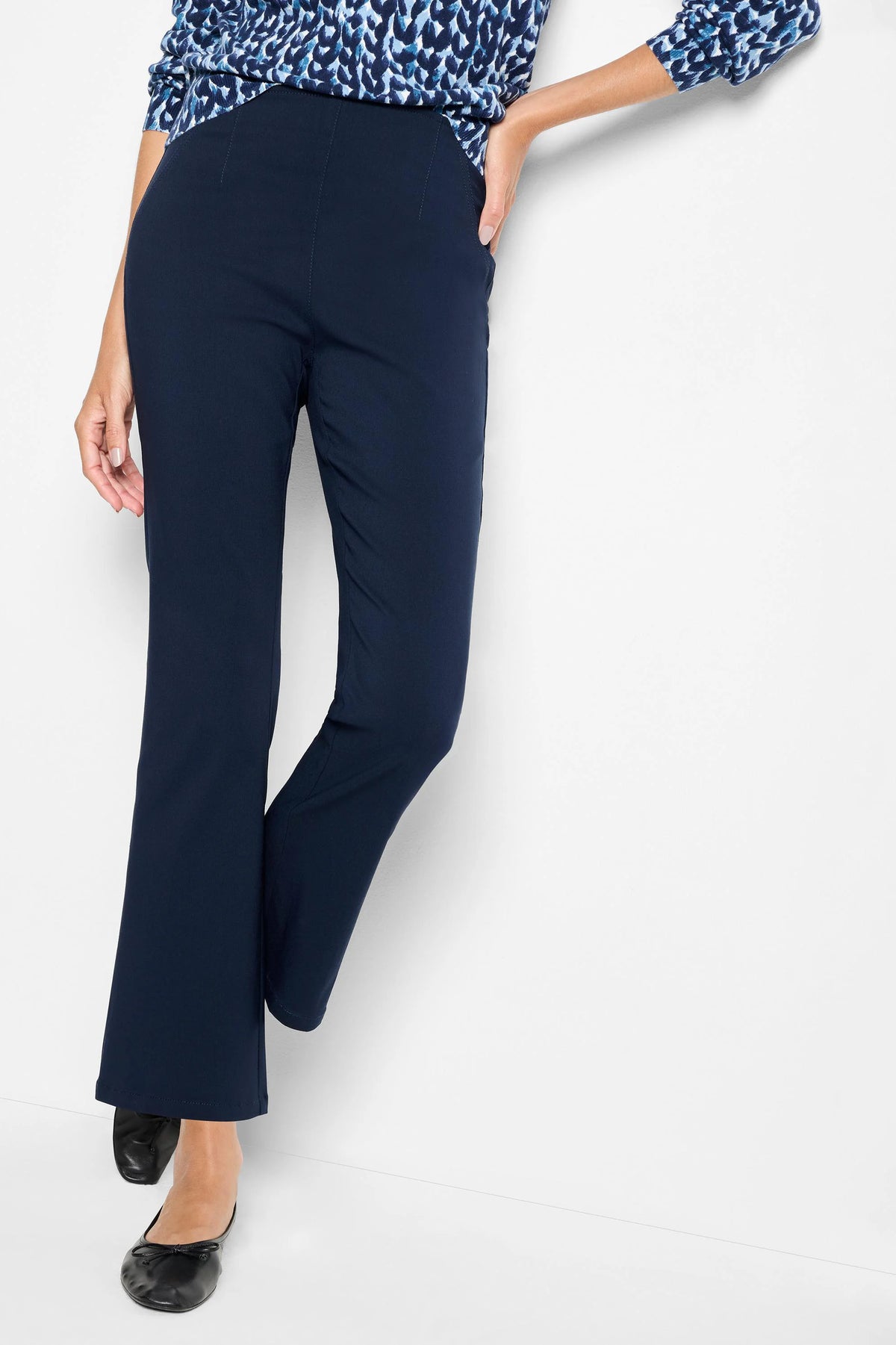 Navy blue bootcut pants on a model, showing a smooth front and subtle vertical seams.
