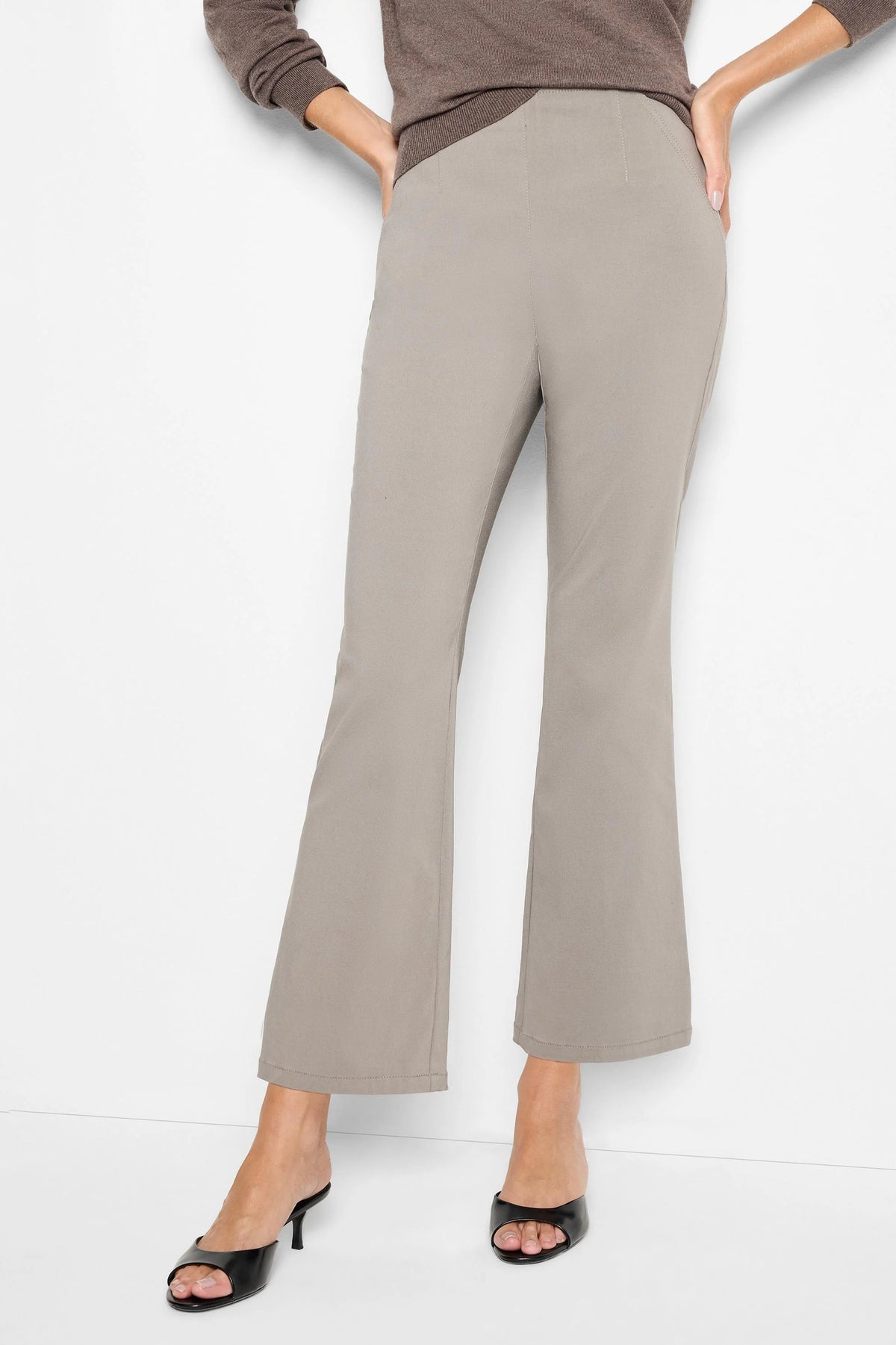 Taupe bootcut pants with a smooth finish and a flat pull-on waistband, modeled on a person.