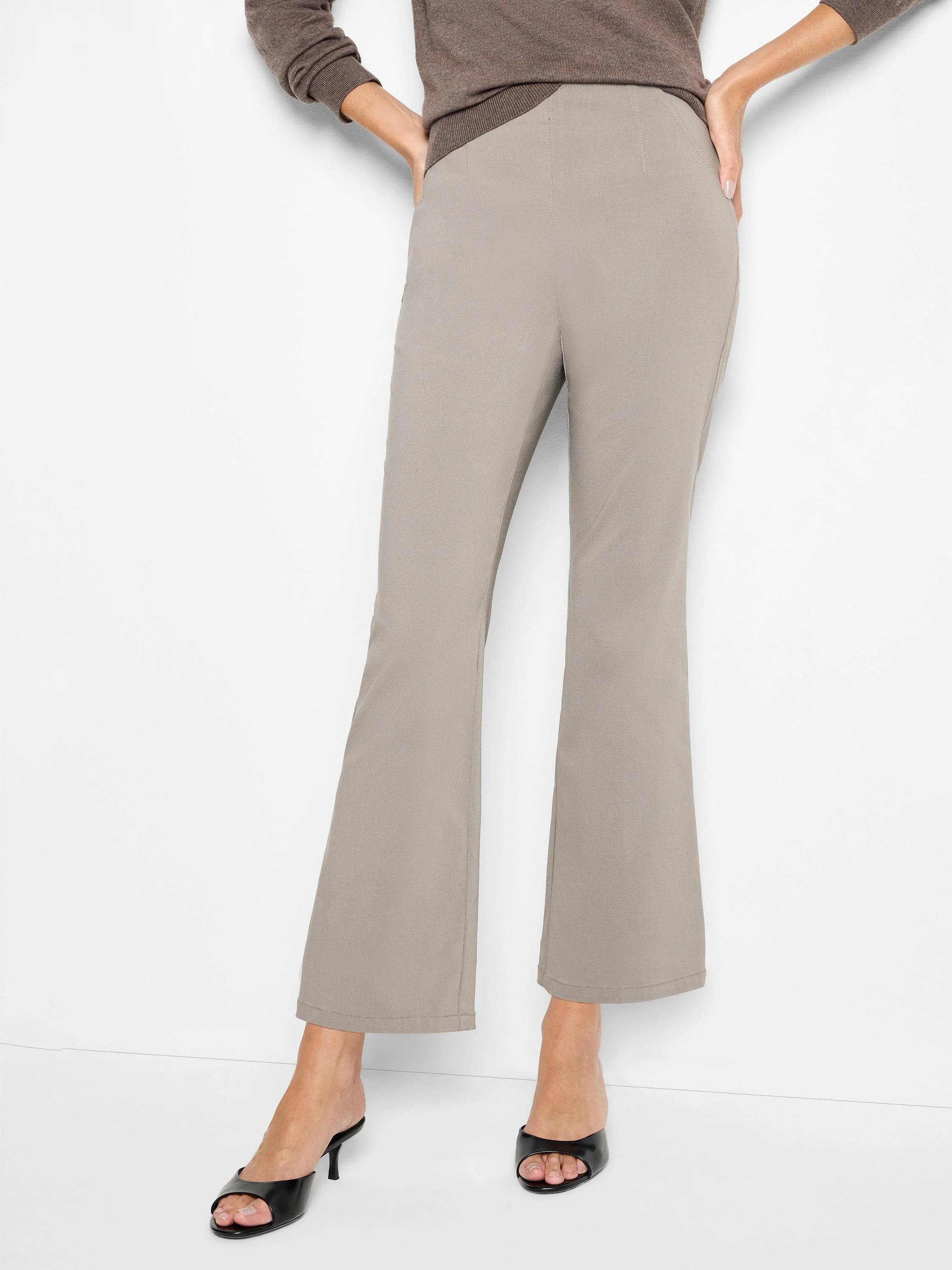 Taupe bootcut pants with a smooth finish and a flat pull-on waistband, modeled on a person.