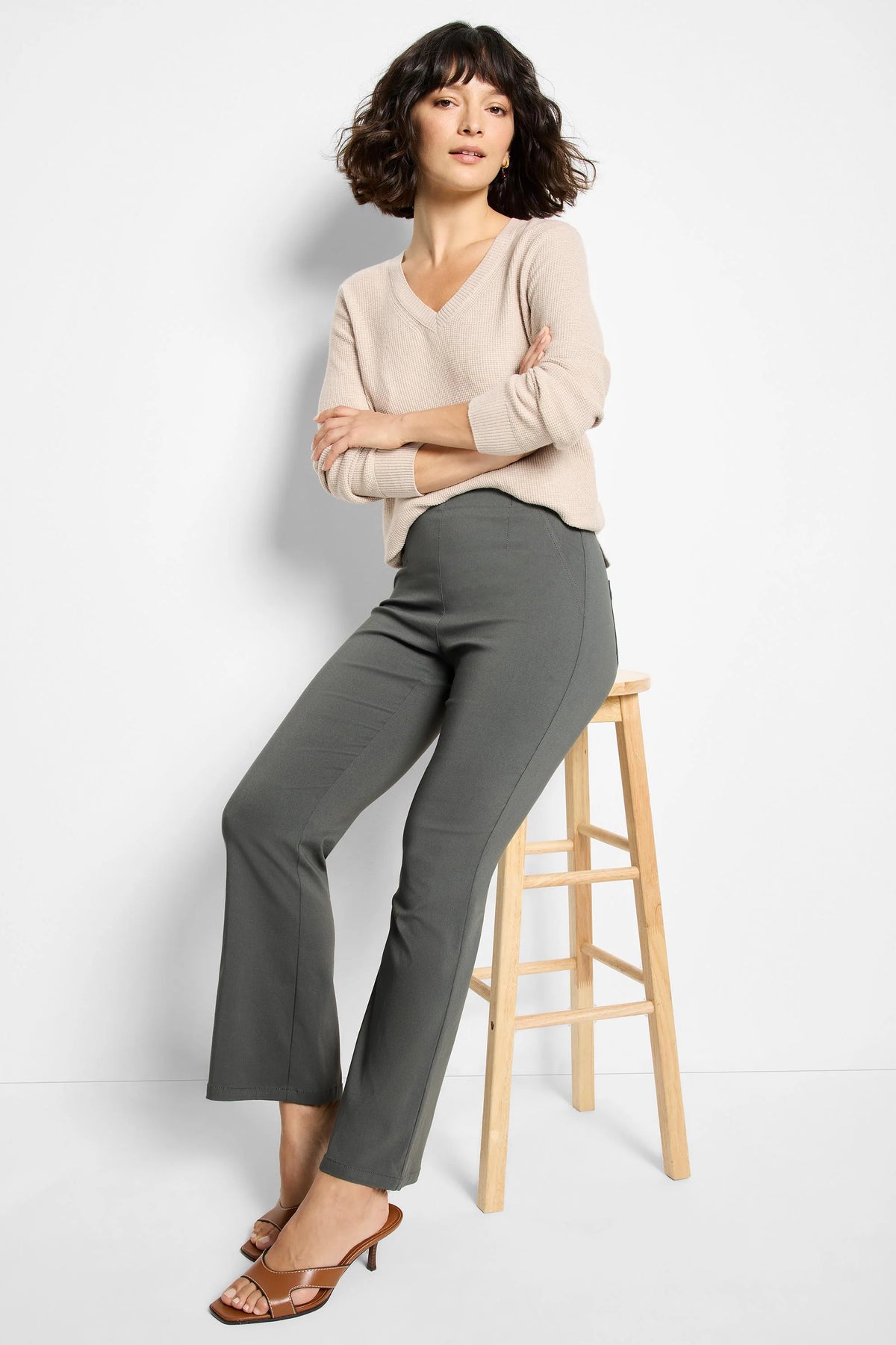 Deep olive bootcut pants, fitted through the hip and thigh, with a subtle flare. Model is seated.