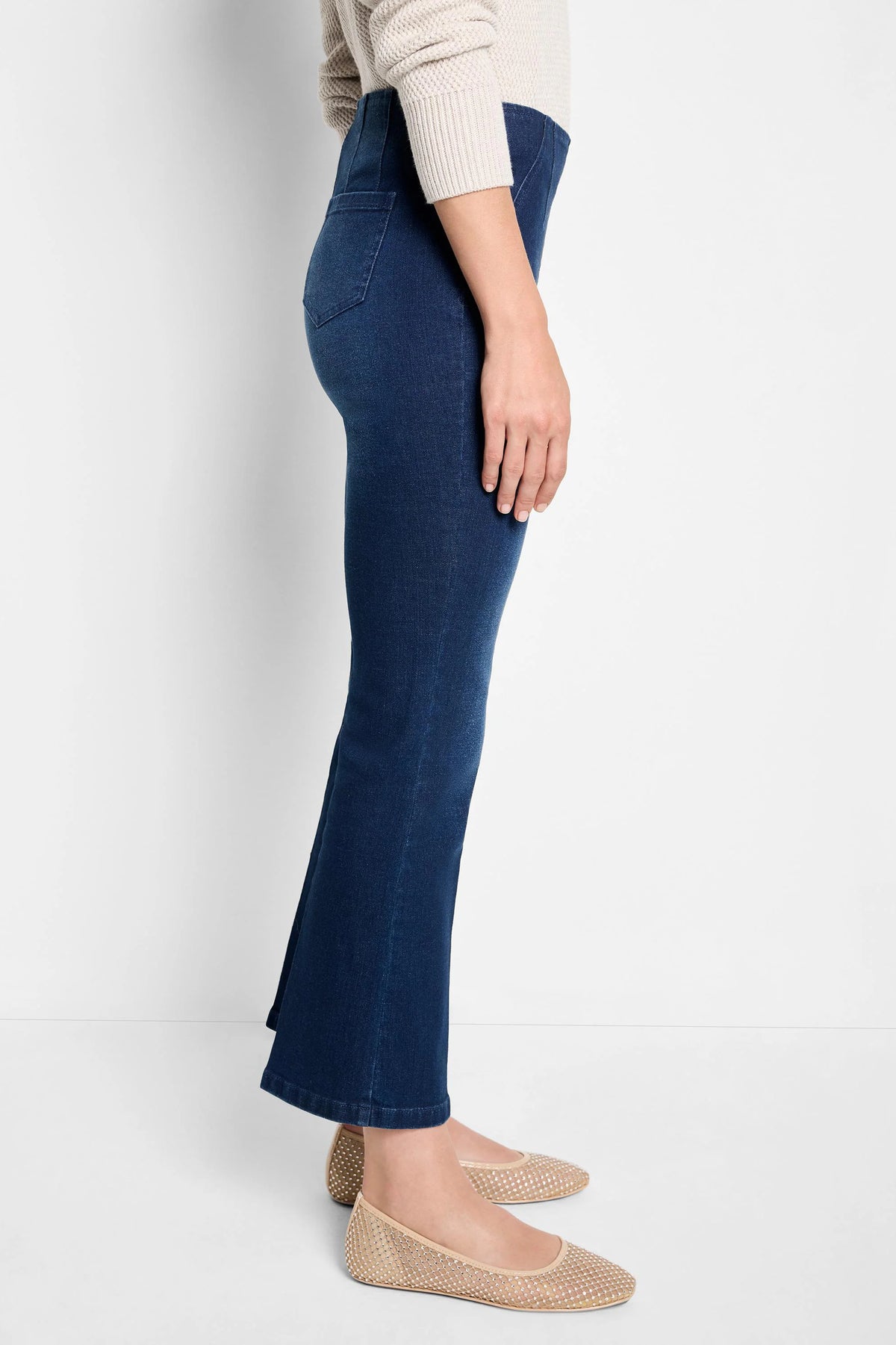 Dark wash boot-cut jeans shown on a model. Jeans are dark blue; model wears beige shoes.