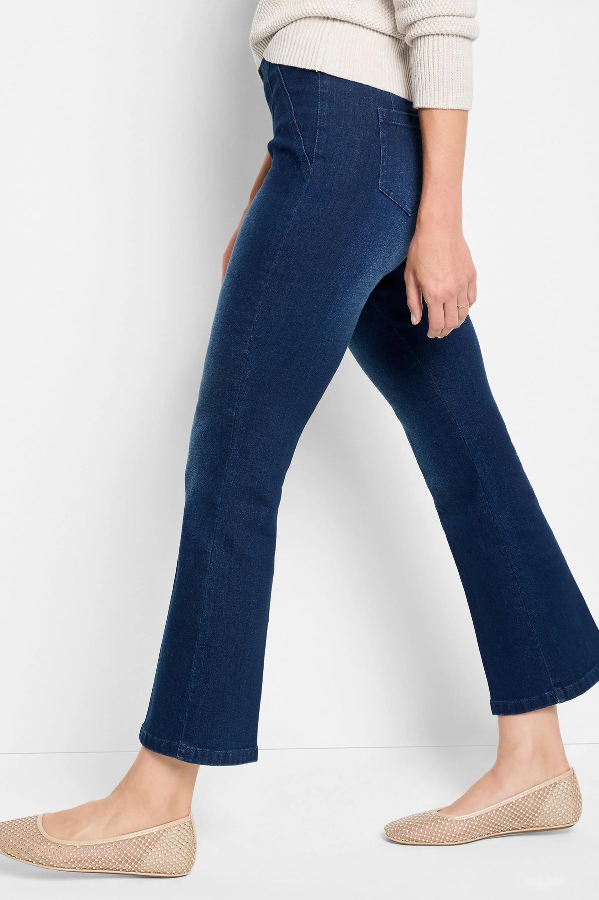 Dark wash boot-cut jeans shown on a model. The jeans are dark blue. The model is also wearing beige flats.