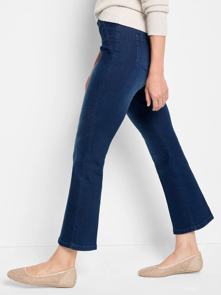 Dark wash boot-cut jeans shown on a model. The jeans are dark blue. The model is also wearing beige flats.