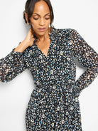 Black dress with cream, blue, and tan abstract spots. Features long sleeves, V-neck with ruffle, and smocked waist.