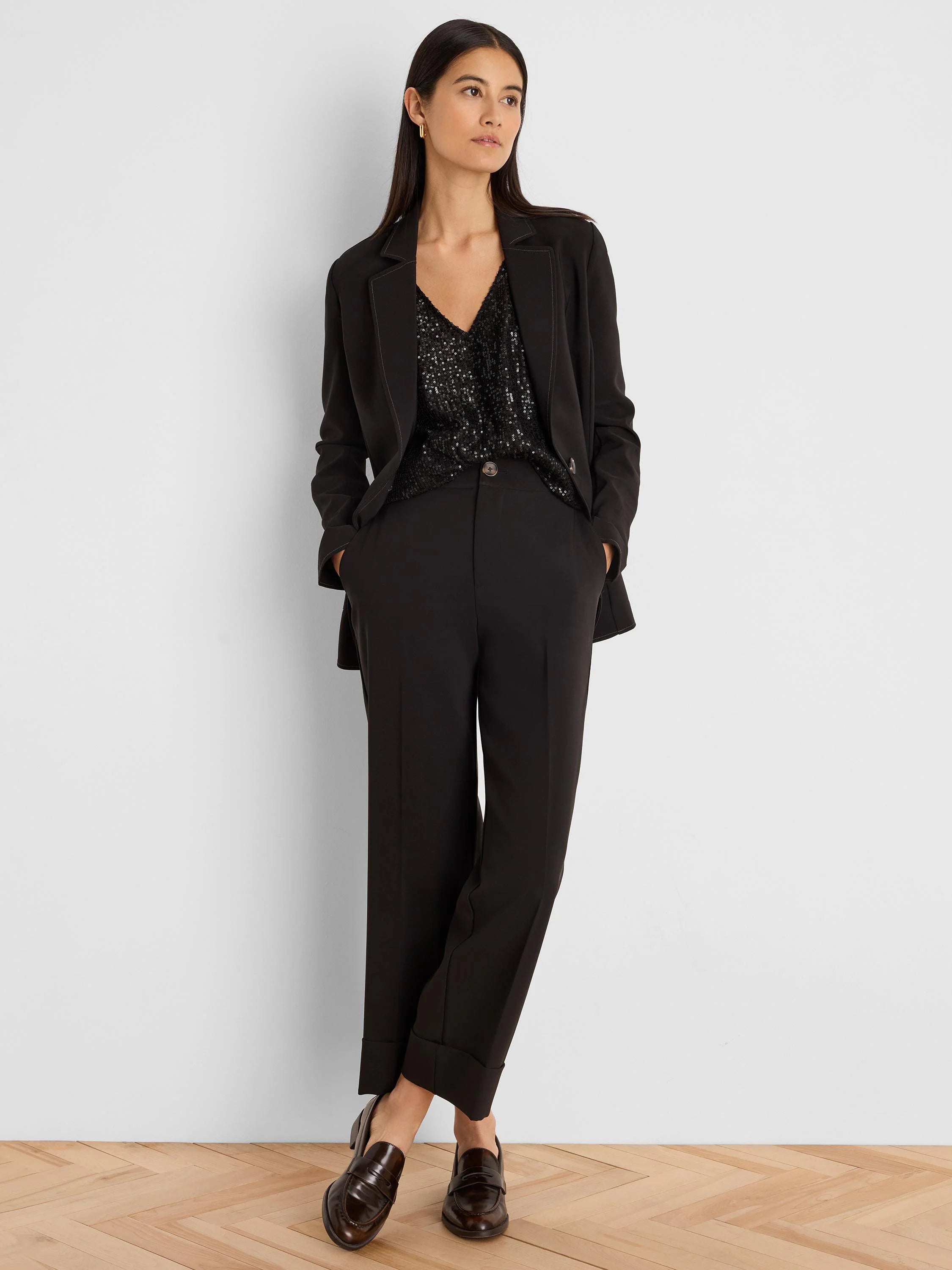 Black blazer with light accent stitching on lapels & seams. Model wears it with a black sequin top & trousers.