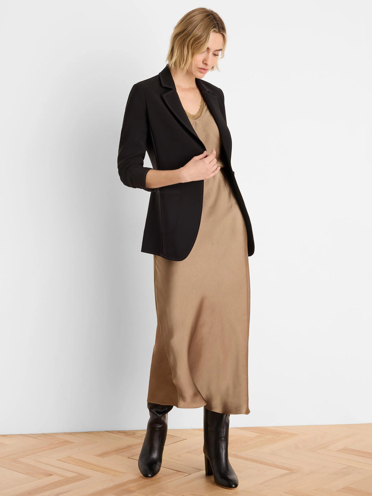 Black blazer with white accent stitching on lapels, front edges, and rounded pockets.