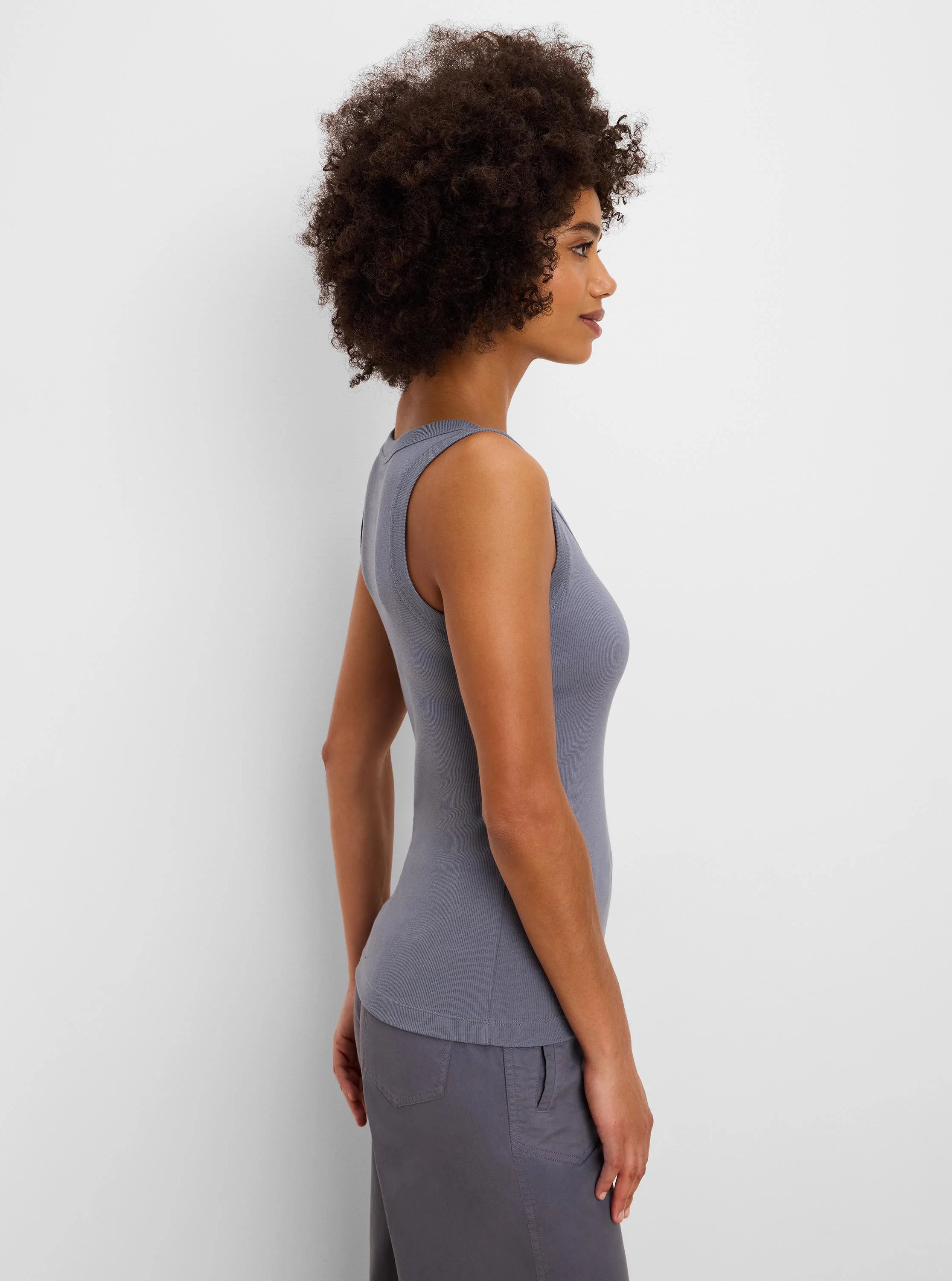 Muted blue-gray ribbed knit scoop neck tank, form-fitting. Model wears in profile view.