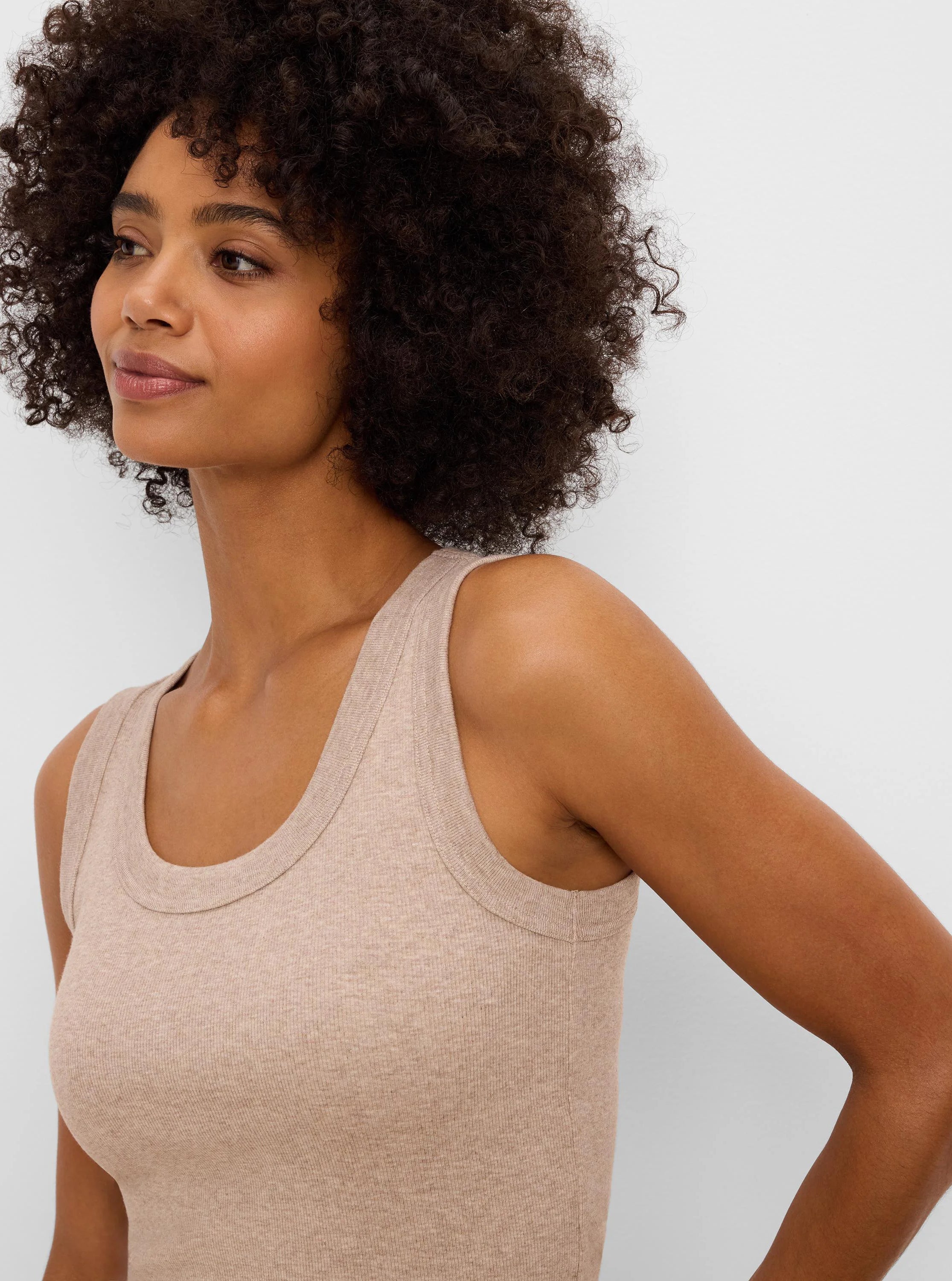 Tan ribbed knit scoop neck tank top. Close-up shows fabric texture and neckline details on model.