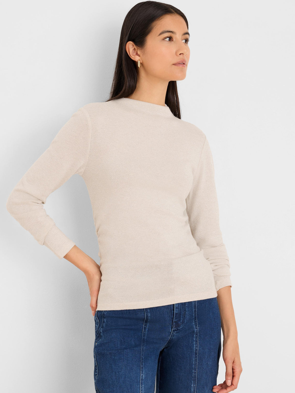Shimmering light beige ruched mock neck top with long sleeves. Fitted silhouette.