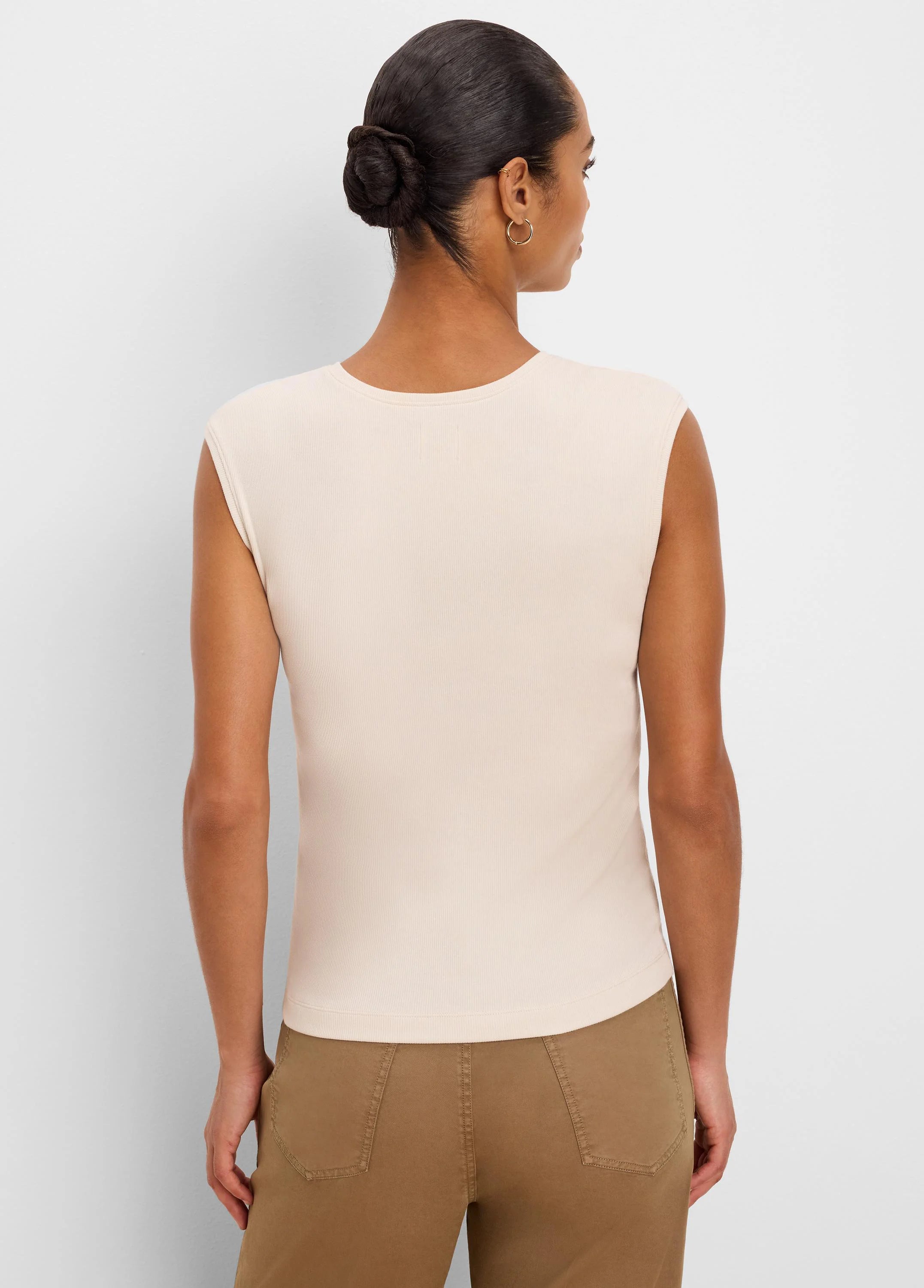 Fitted, light beige ribbed knit sleeveless tank top, shown from the back on a model.