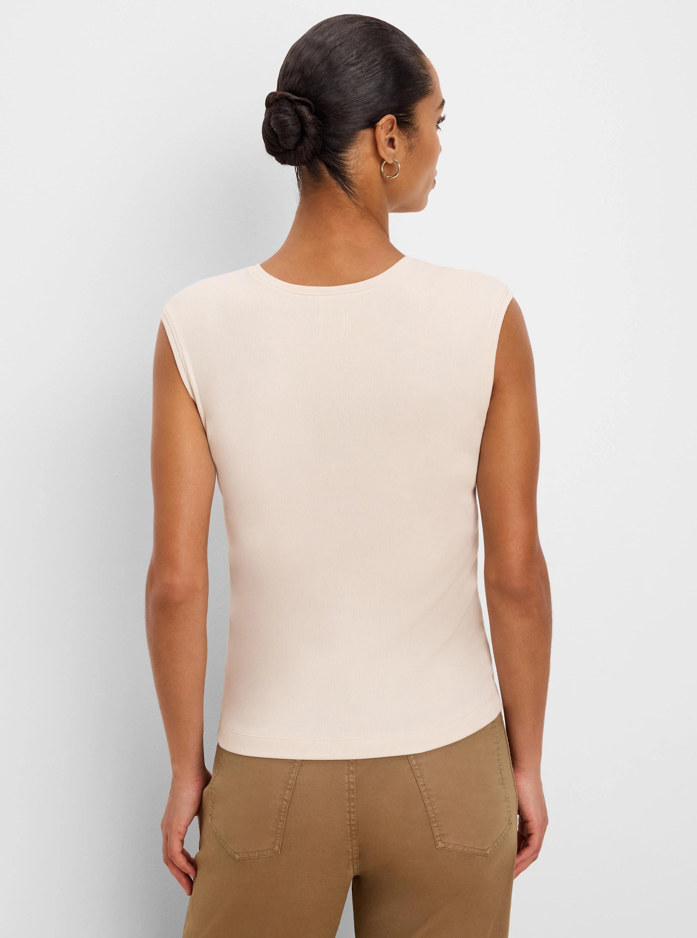 Fitted, light beige ribbed knit sleeveless tank top, shown from the back on a model.