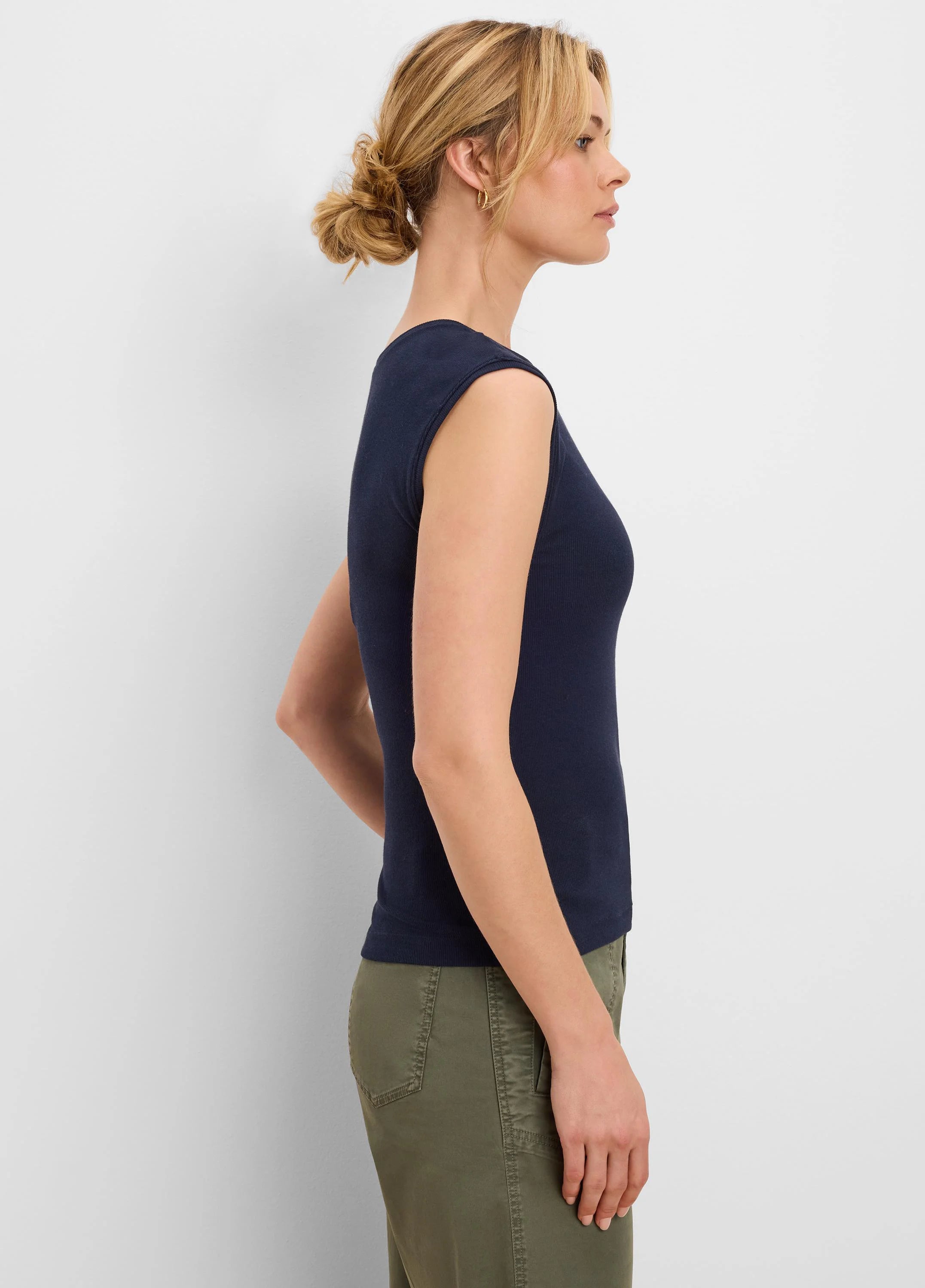 Navy blue ribbed knit tank top on a model. Fitted, sleeveless, wide neckline.