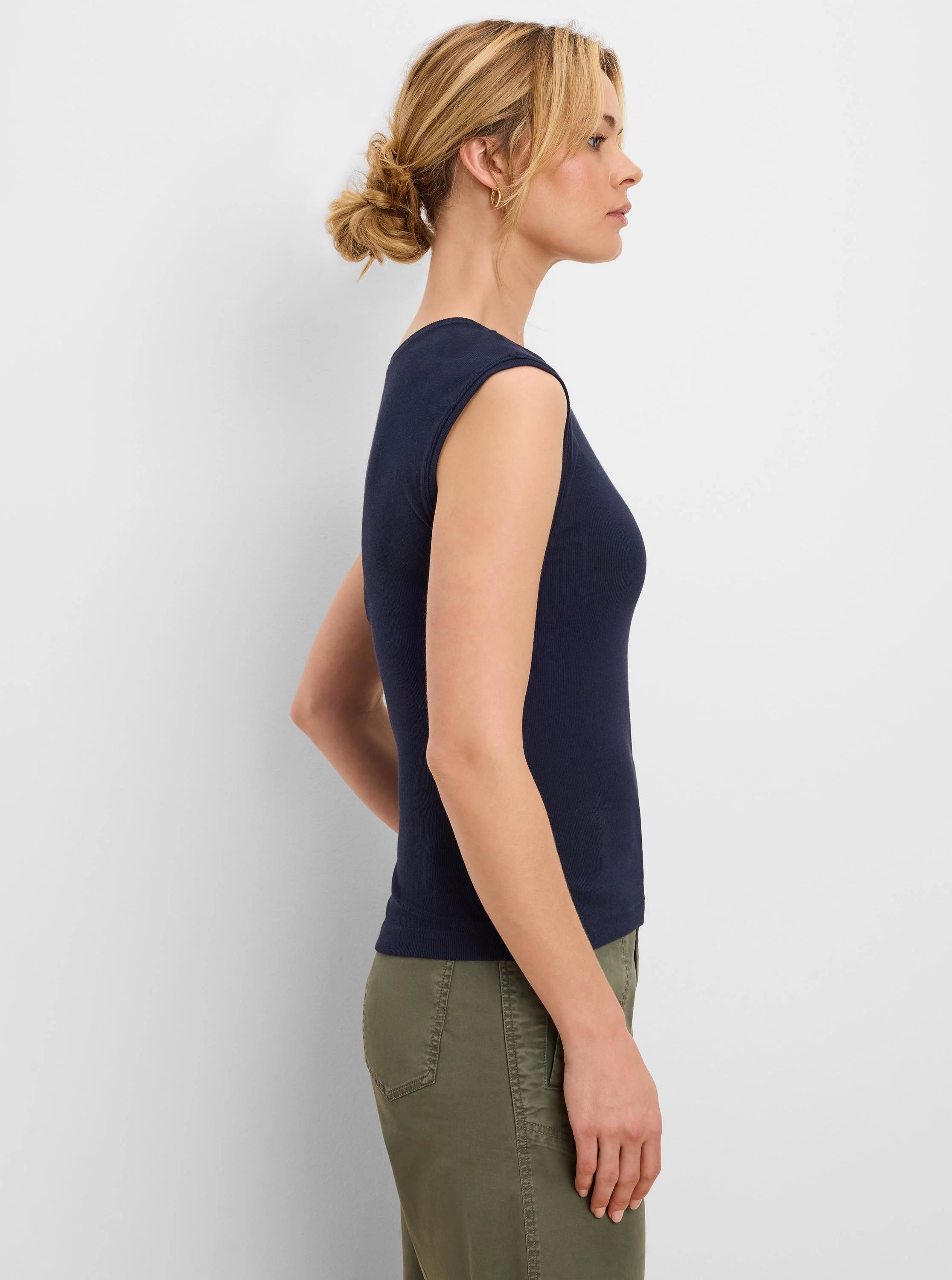 Navy blue ribbed knit tank top on a model. Fitted, sleeveless, wide neckline.