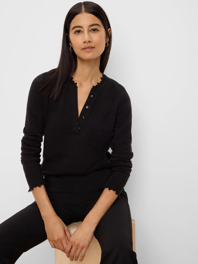 Black Henley sweater with button placket, ruffled neckline, and ruffled cuffs.