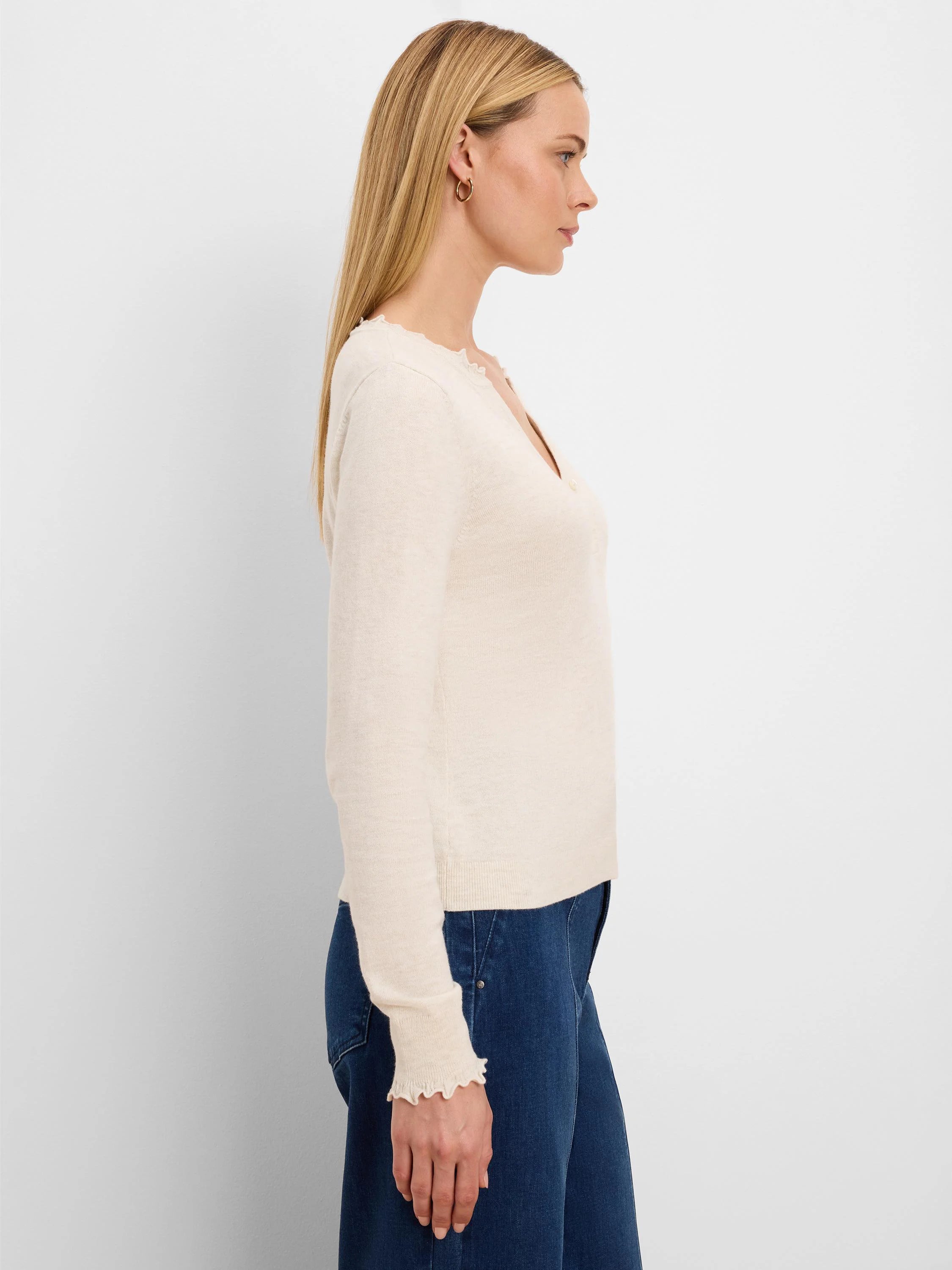 Cream Henley sweater with ruffle trim on the neckline and cuffs.