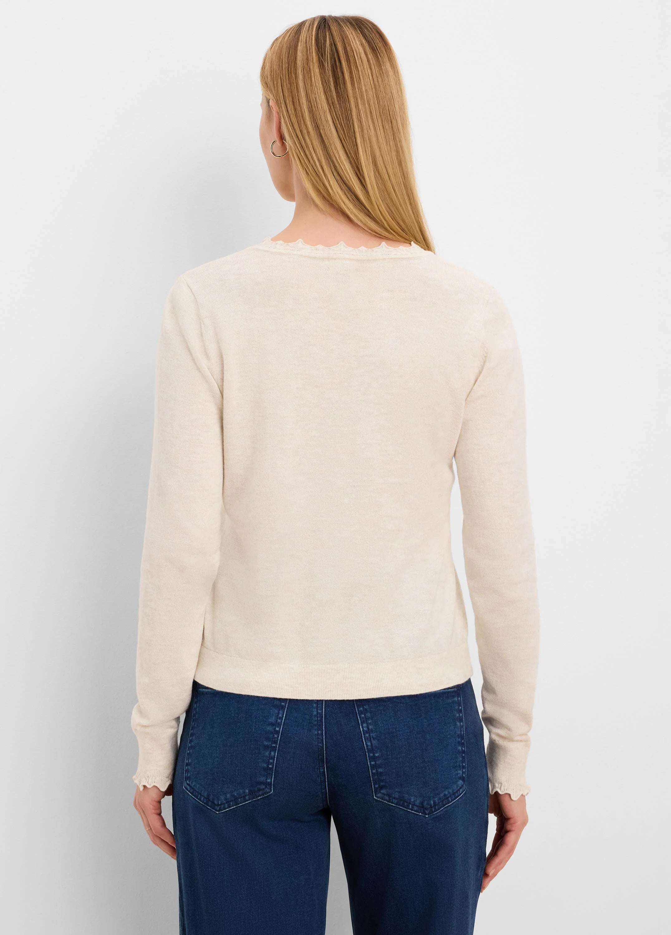 Cream long-sleeve sweater with ruffled neckline and cuffs, modeled from behind.