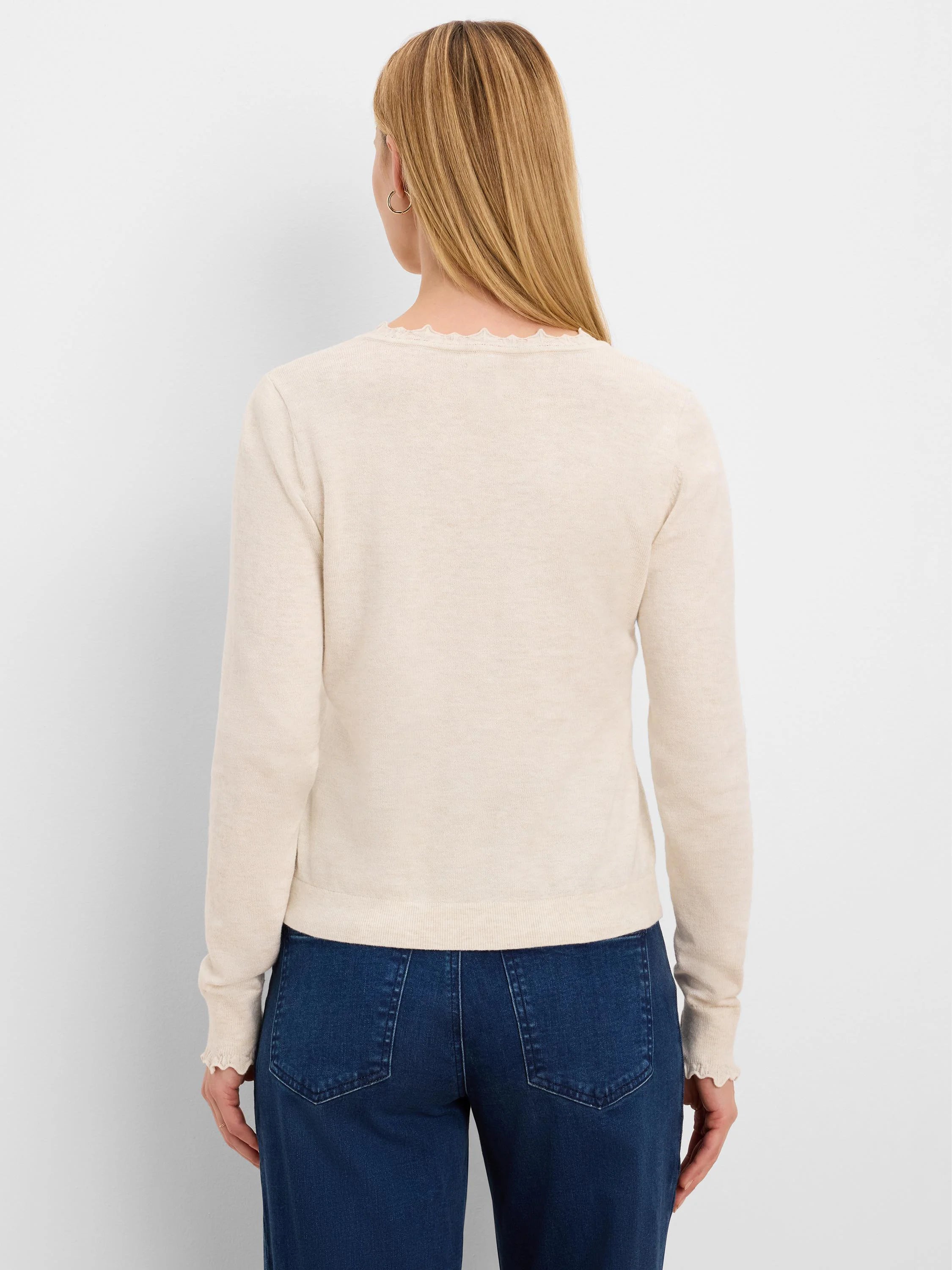 Cream long-sleeve sweater with ruffled neckline and cuffs, modeled from behind.